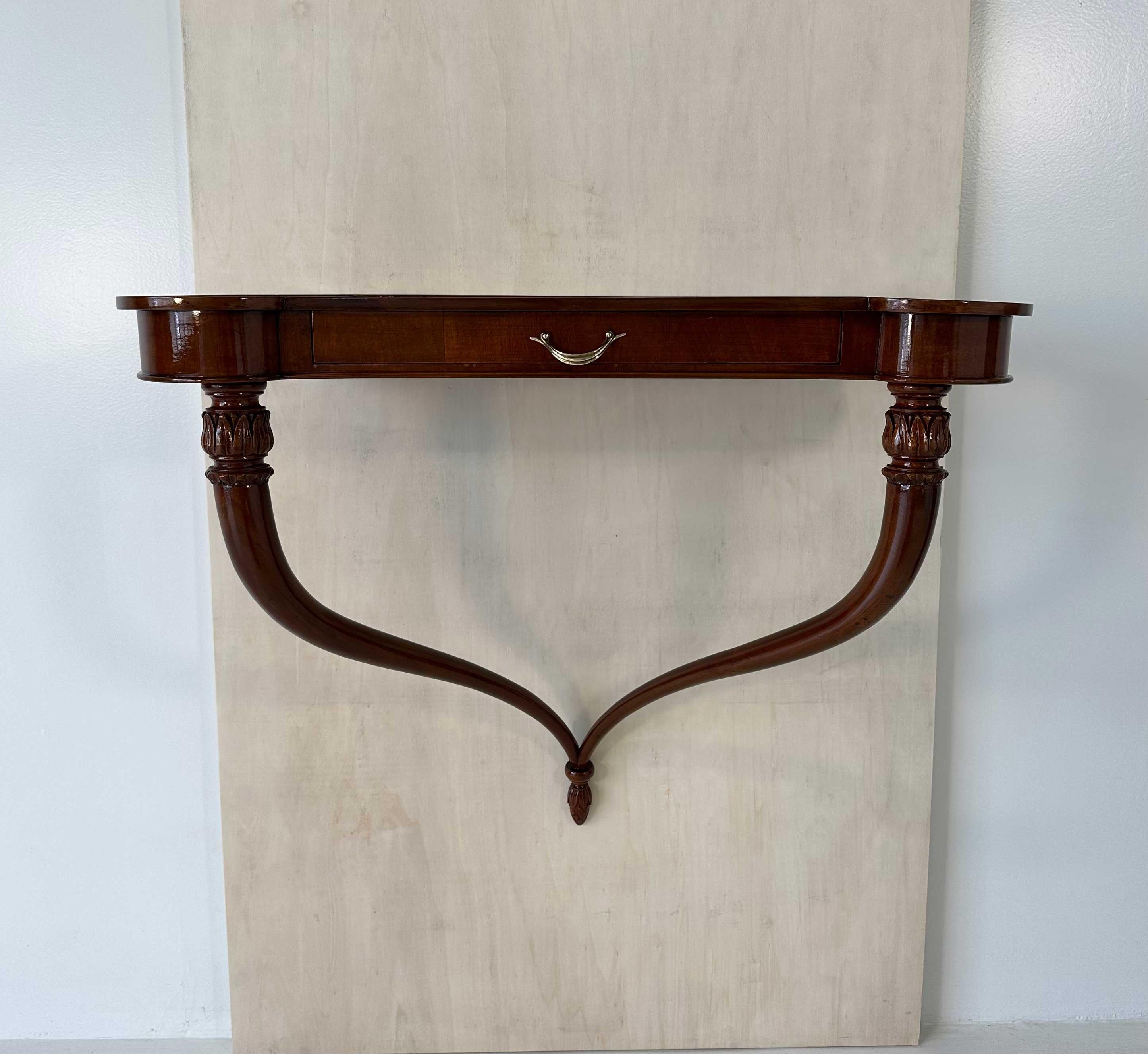 This elegant Art Deco console table was produced in Italy in the 1930s. 
It features a top with a comfortable drawer and sinuous shaped legs and it is completely in walnut with brass handles.

It is a suspended console and can be hung on the wall