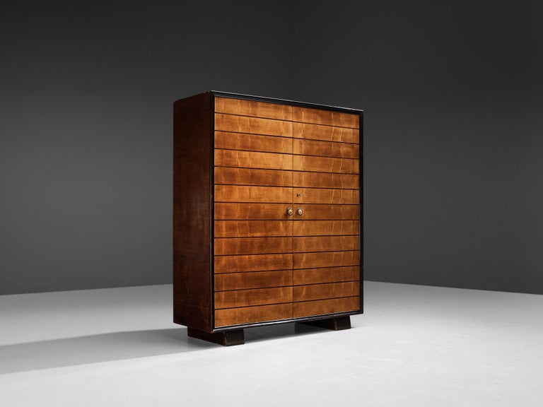 Italian wardrobe, maple, dark stained lacquered wood, Italy, 1940s

This elegant Italian wardrobe is designed in a strong geometric Art Deco style. The dark stained wooden sides frame the two doors with a striped decoration in maple. The warm