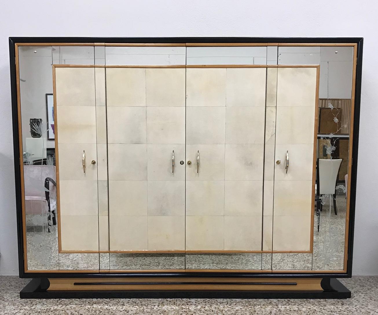 This Italian wardrobe was produced in the 1940s in the style of Osvaldo Borsani.
The front of the doors is covered with parchment with maple details while the structure is in black lacquered wood.
The original mirrors are sandblasted with elegant