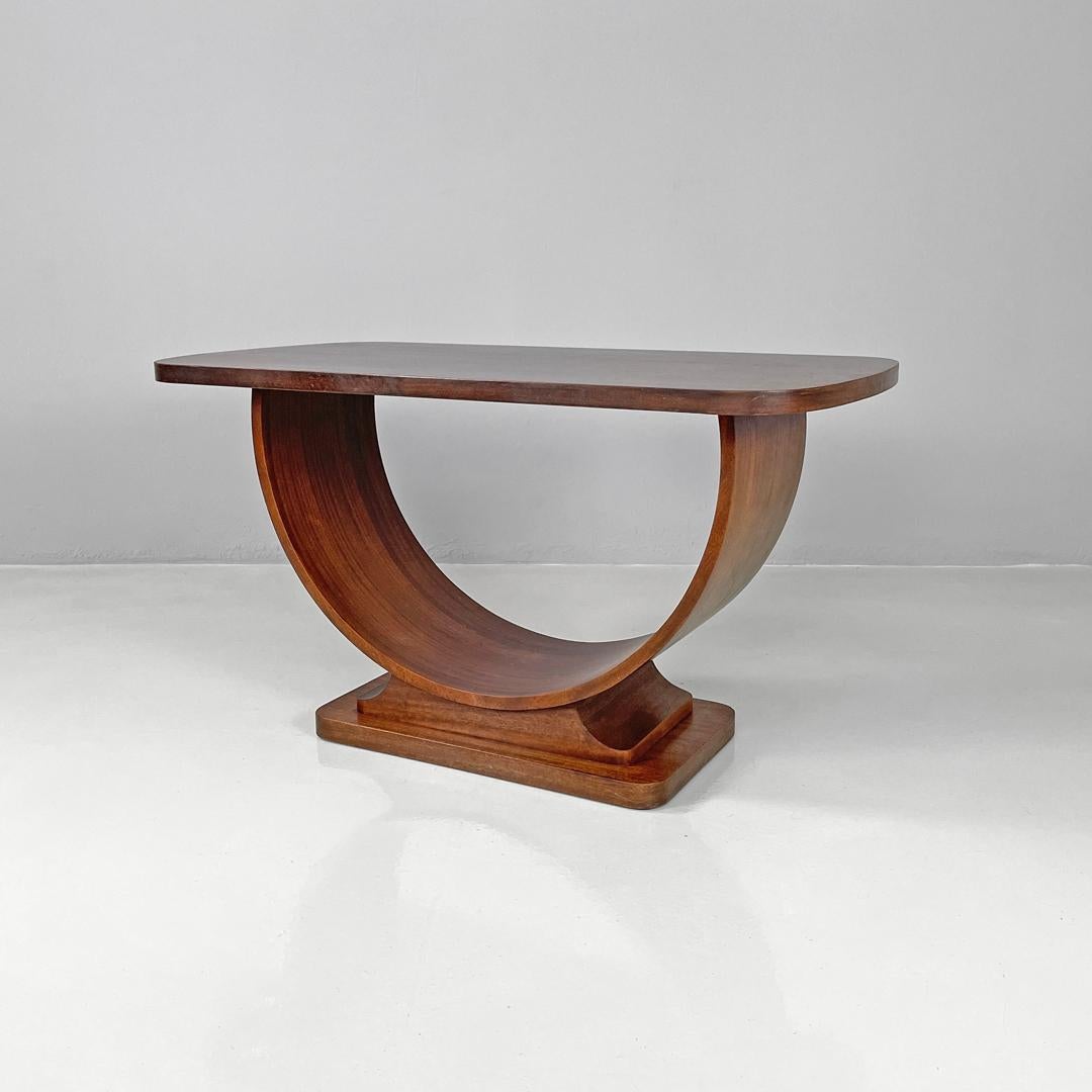 Table basse italienne Art déco avec pieds en demi-cercle, années 1930
Table basse avec base rectangulaire en bois. Le plateau a des angles arrondis, les deux pieds dessinent un demi-cercle qui repose dans sa partie centrale sur une structure aux