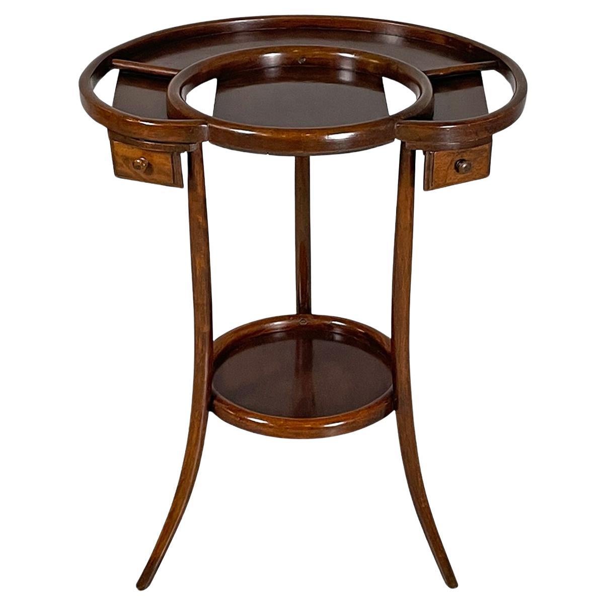 Italian art deco coffee tables, 1900s
Pair of service tables or coffee tables entirely made of wood. The rounded top has rounded profiles that delimit an internal circular space and an edge, on the sides there are two holes. Under the top there are