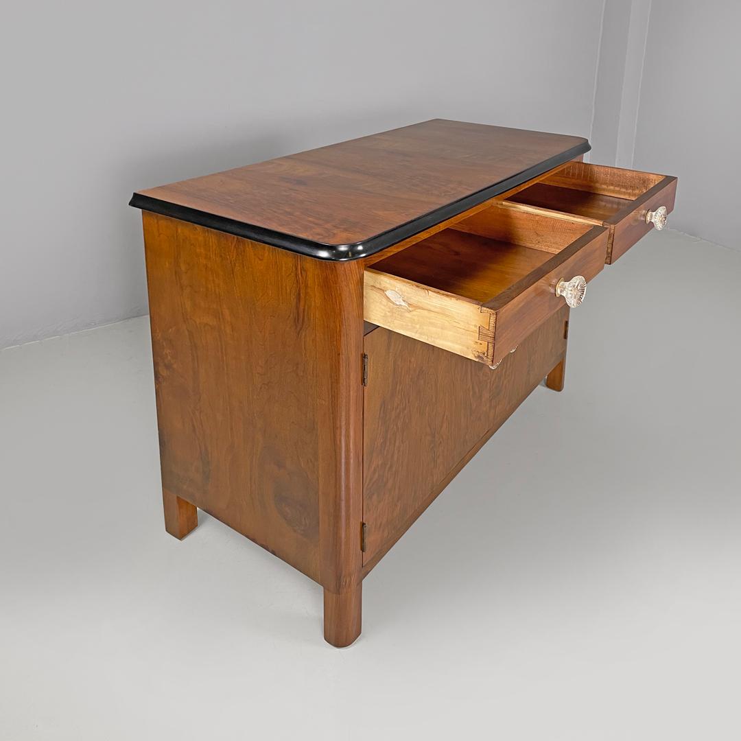 Italian Art Deco wooden dresser two drawers with glass transparent handles 1940s
Wooden sideboard or cupboard. The top of the cabinet is rectangular and has shaped profiles painted in black, there are two drawers and two doors with round handles in