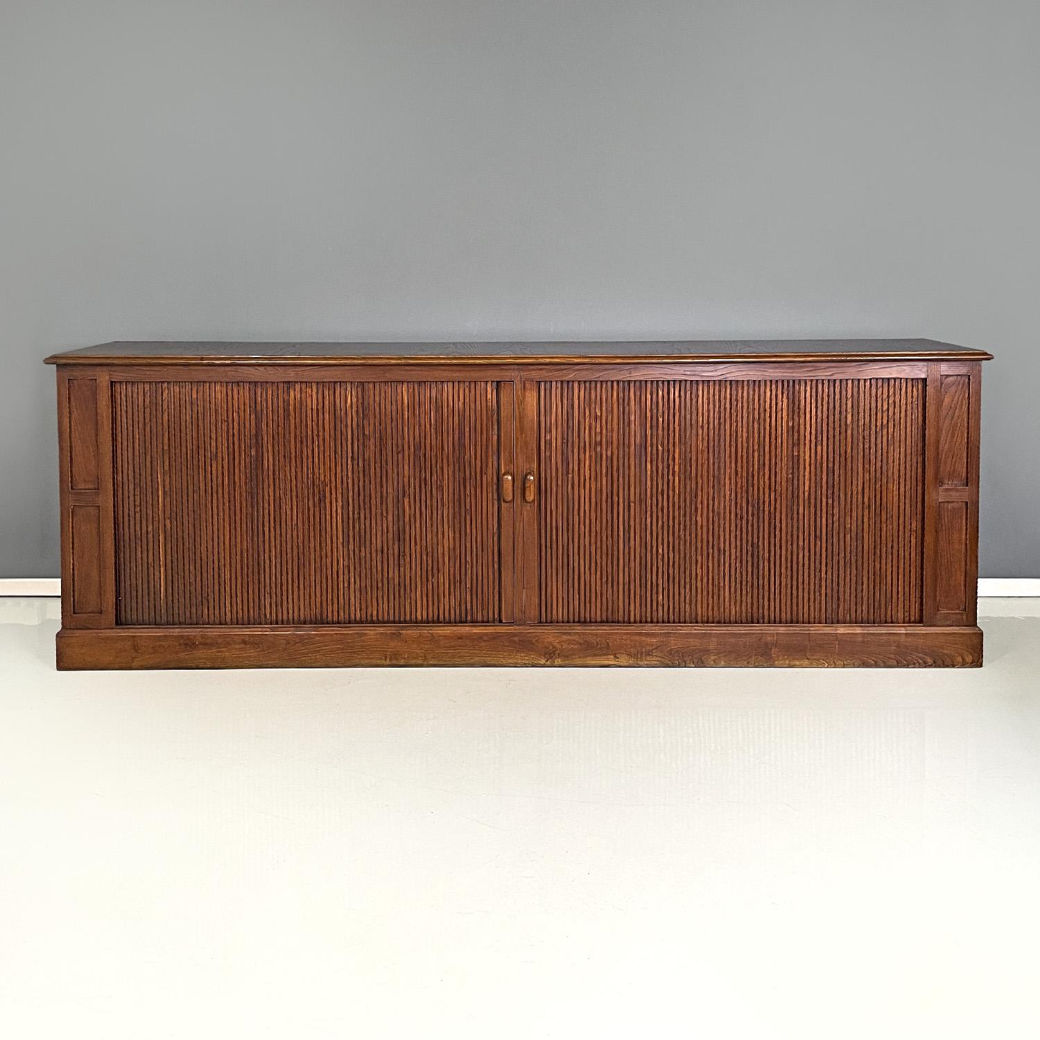 Italian Art Deco wooden sideboard with shutter opening, 1920s
Sideboard with rectangular base made entirely of wood. The top is composed of a smooth rectangular wooden board with shaped edges and slightly wider than the central structure. It has a