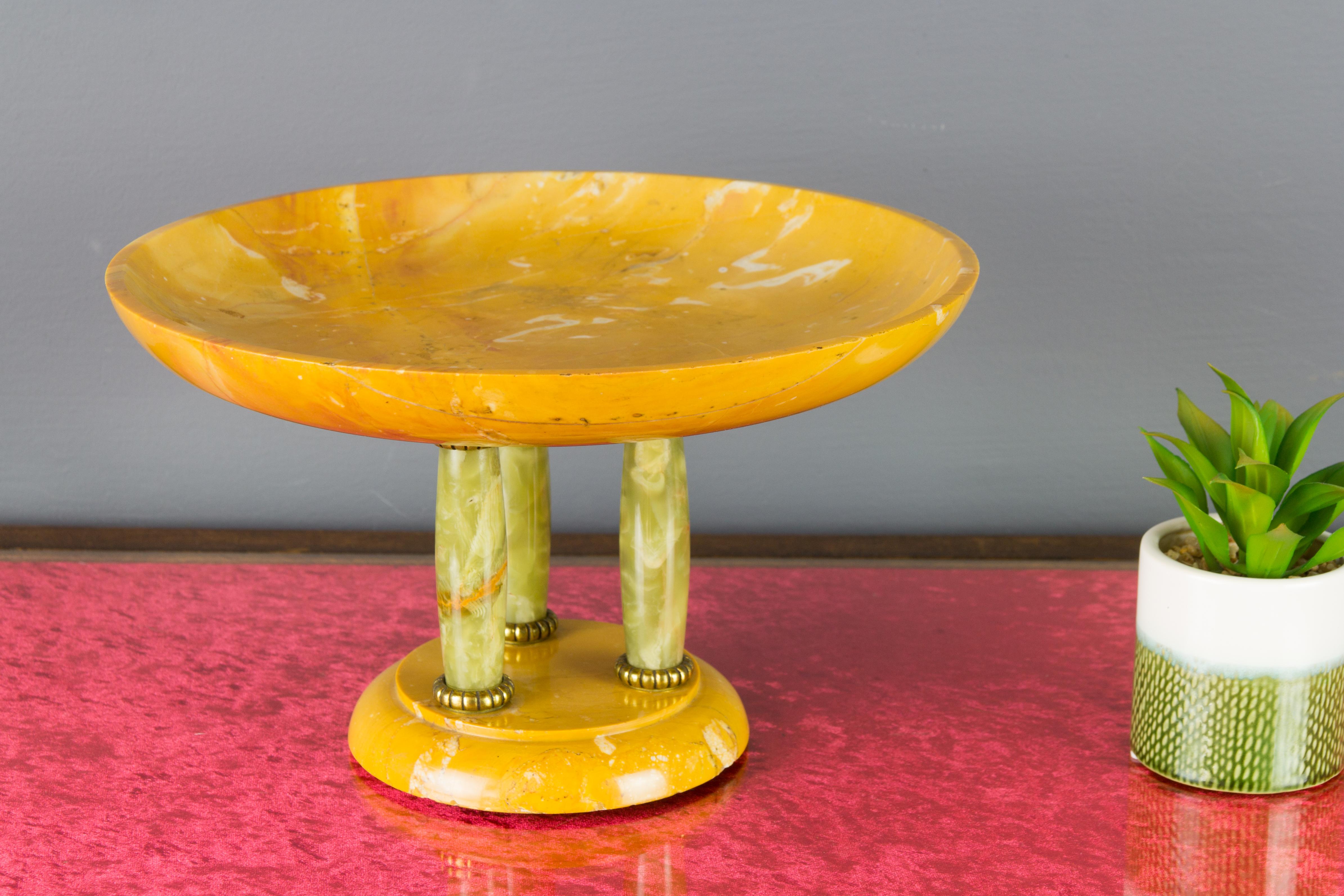 Beautiful Italian Art Deco centerpiece or tazza. Circular base and shallow bowl top made of yellow alabaster and raised on three-light green onyx columns with brass rims.
Dimensions: height: 18 cm / 17.08 in; diameter: 30 cm / 11.81 in.