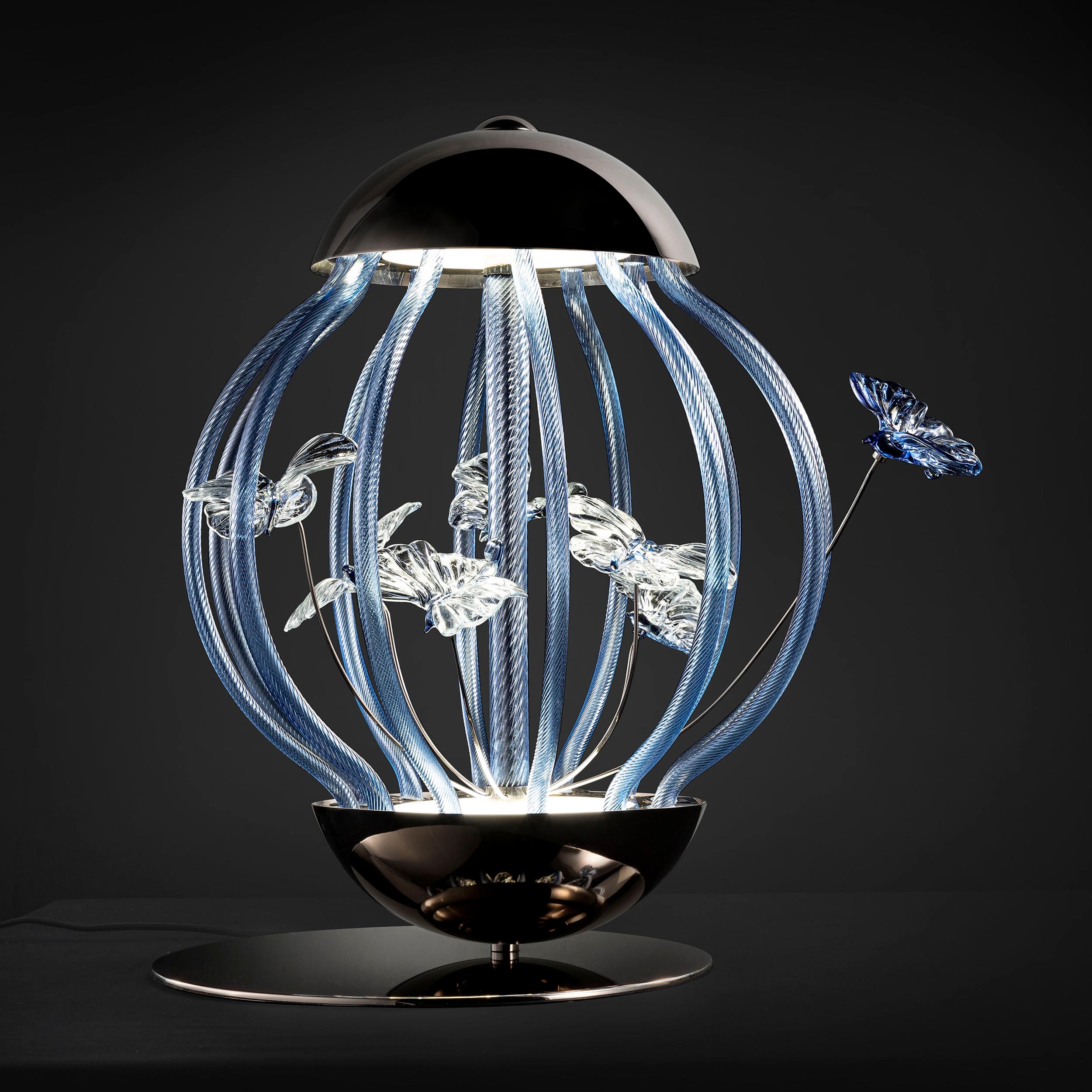 Uno squisito pezzo di design artistico italiano. Lampada da tavolo artistica Cage in vetro blu Iceberg di Multiforme con farfalle modellate a mano da maestri vetrai. Un oggetto che combina il savoir-faire artistico di Murano con i dettagli tecnici