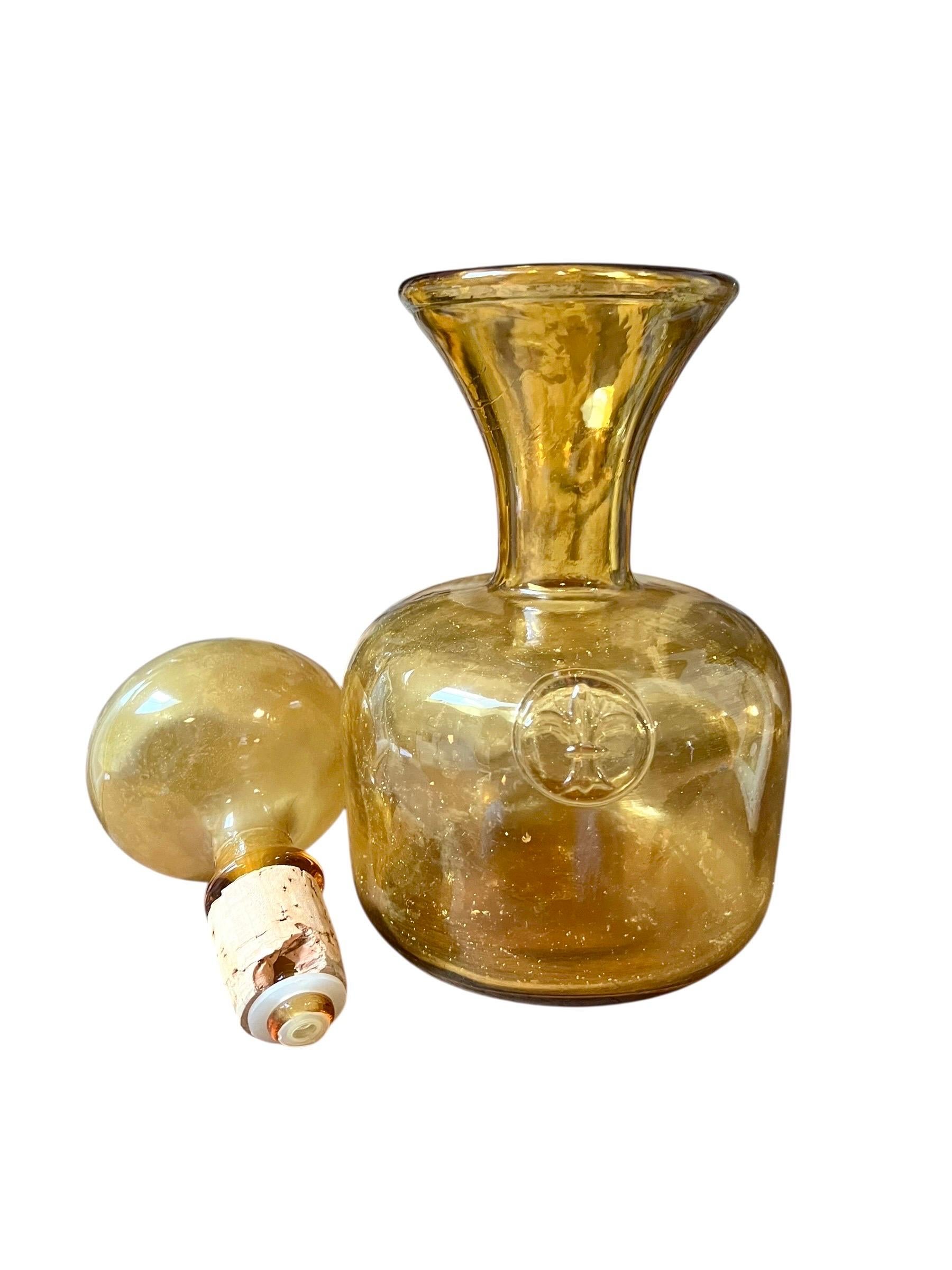 Belle carafe en verre d'art italien des années 1960.

La carafe avec une couleur ambrée, un jaune-orange audacieux et un impressionnant bouchon en verre soufflé, qui montre toute la technique des artisans italiens de Murano par exemple.

La base est