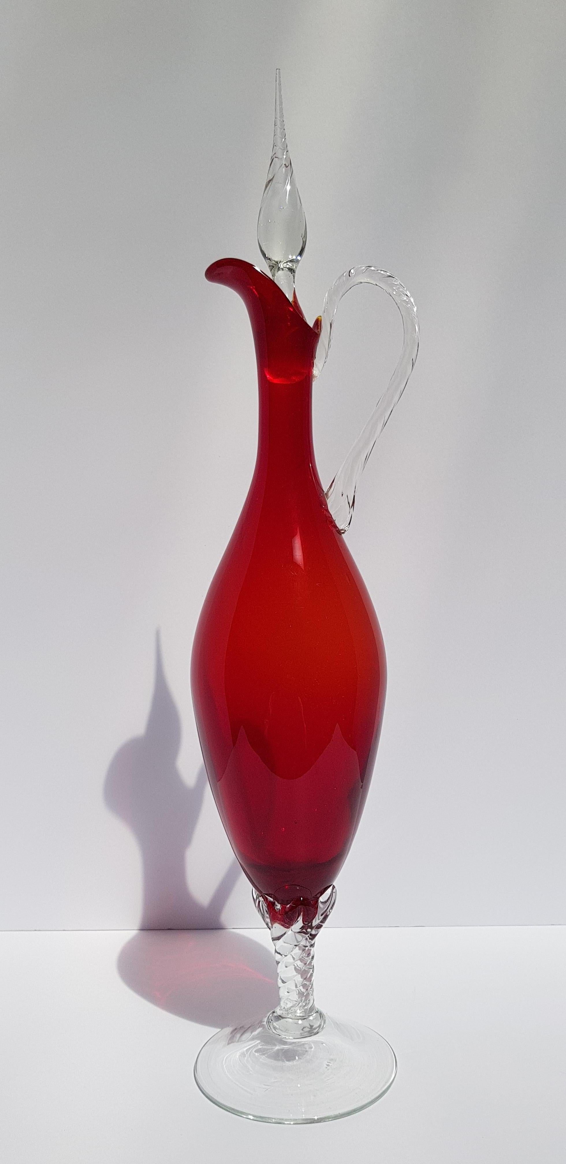 A monumental Italian art glass decanter, ewer, cruet, vase or bottle with stopper in a rich ruby red color attributed to Empoli. Hand blown of the finest art glass in a classic mid century modern color. This art glass decanter stands an impressive