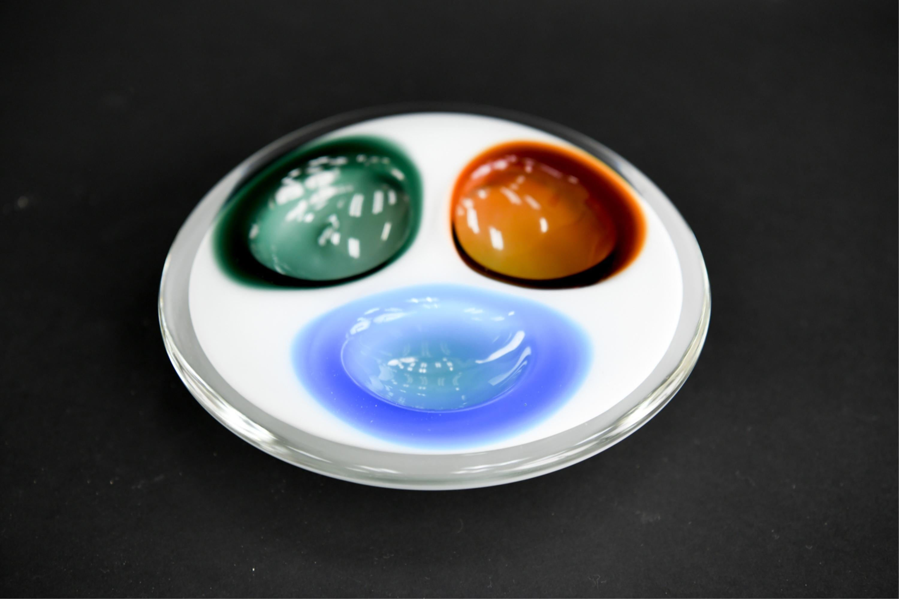 Sculptural glass dish with three colorful compartments.