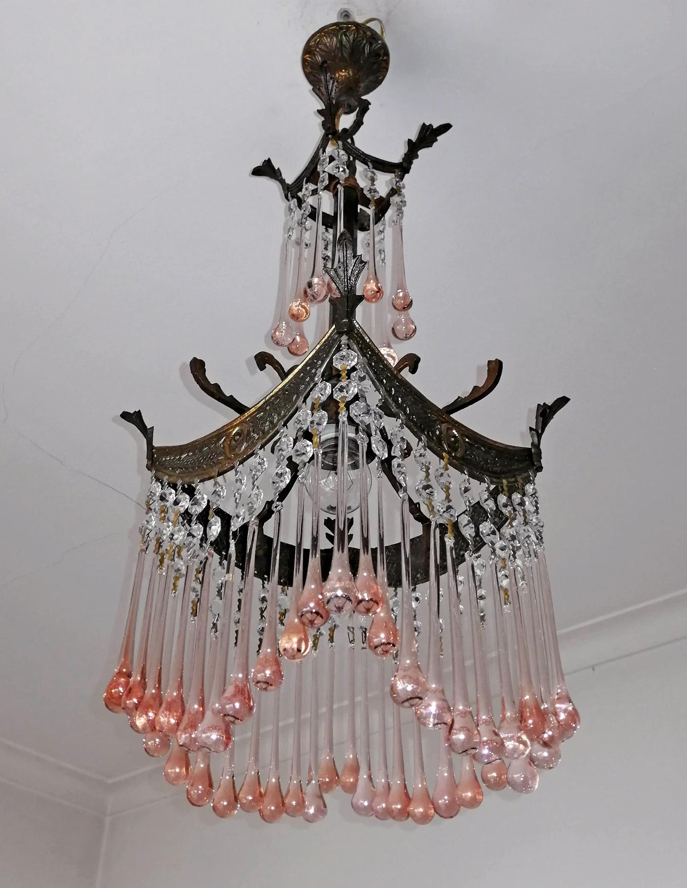 Beautiful antique Italian Art Nouveau and Art Deco Murano pink crystals tear drop bronze chandelier in a radial pattern with a very sparkling effect typical of Hollywood style and glamour. The fixture is brass and the glass is hand