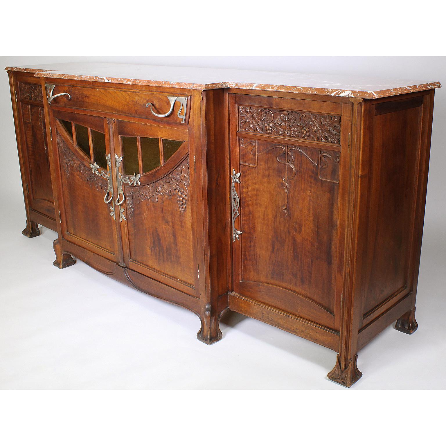 A fine Italian 19th-20th century Art Nouveau carved walnut buffet server by Vittorio Valabrega (1861-1952). The finely carved walnut body with twin center doors carved with grape vines, fitted with molded yellow-Craft-glass panels above an apron