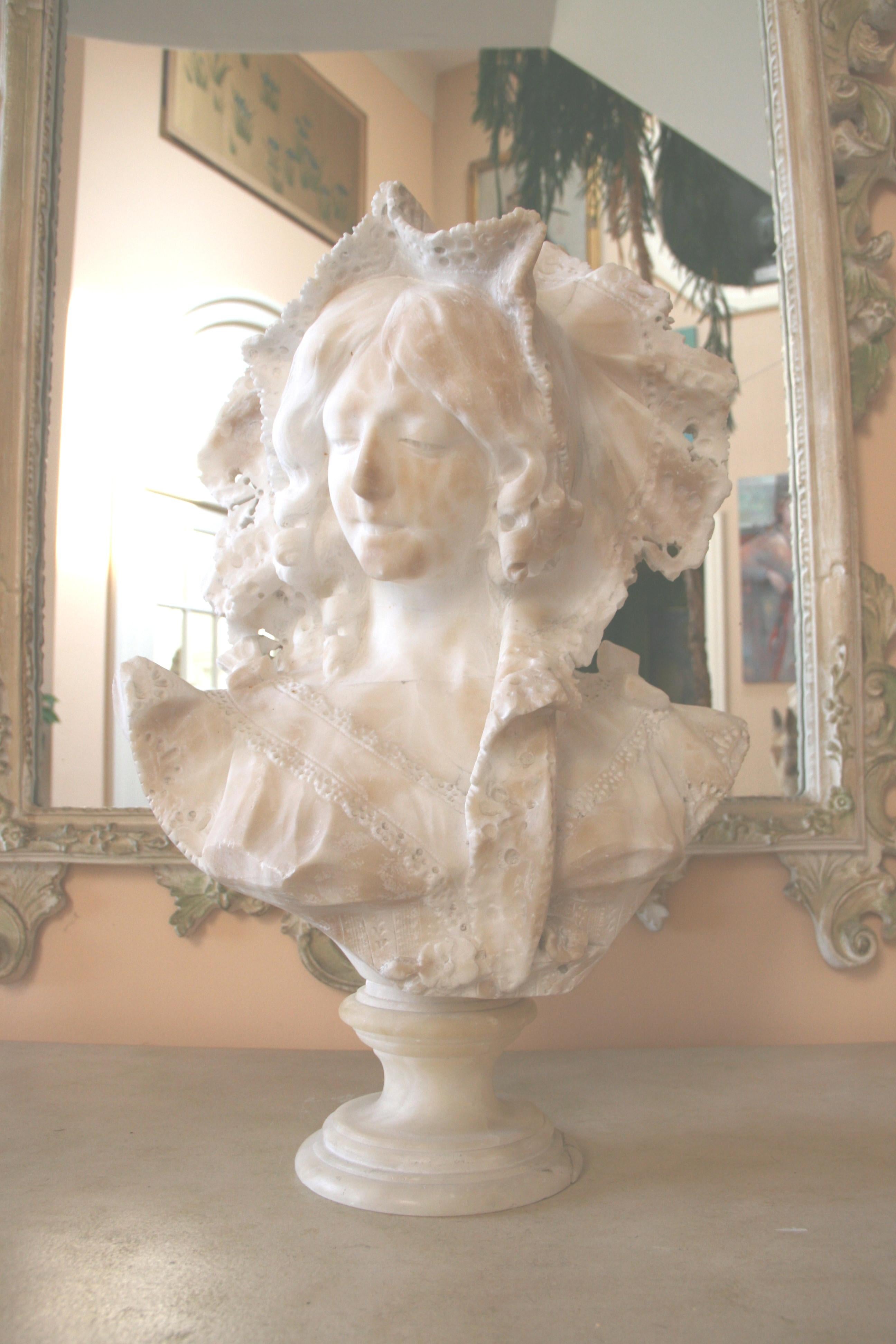 Marbre blanc Art Nouveau courbé à la main  buste d'une jeune femme. Son chapeau élaboré encadre un beau visage. Style vestimentaire de la période Art nouveau de la fin du XIXe siècle. Le buste repose sur un socle rond en marbre.
Les taches de brun