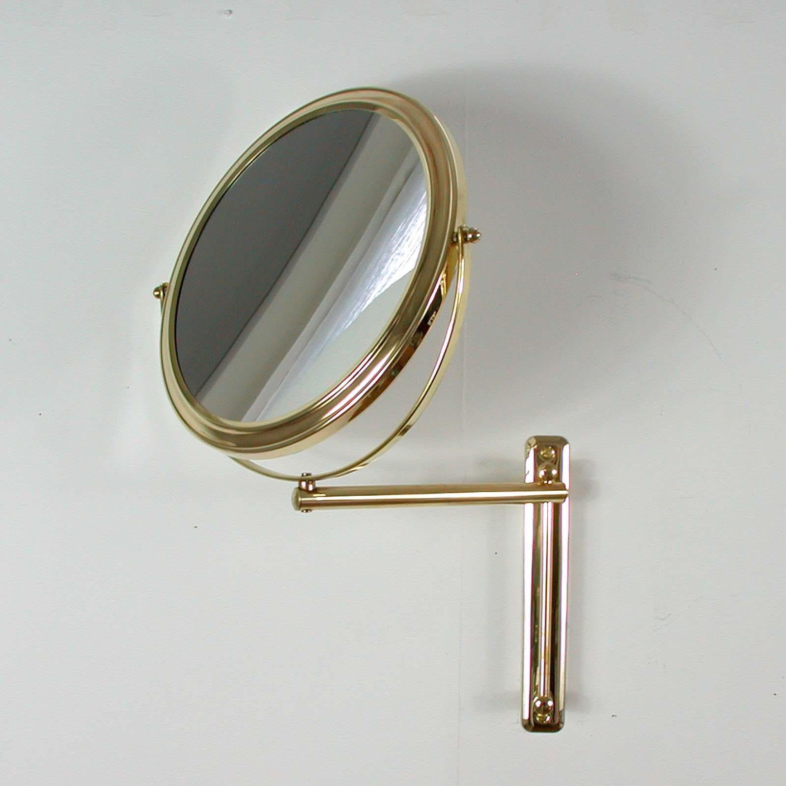 Cet élégant miroir de courtoisie rond a été conçu et fabriqué en Italie dans les années 1950-1960. Il est doté d'un cadre rond en laiton et d'un bras mural en laiton. Le miroir est réglable en hauteur. Il peut également être tourné de gauche à