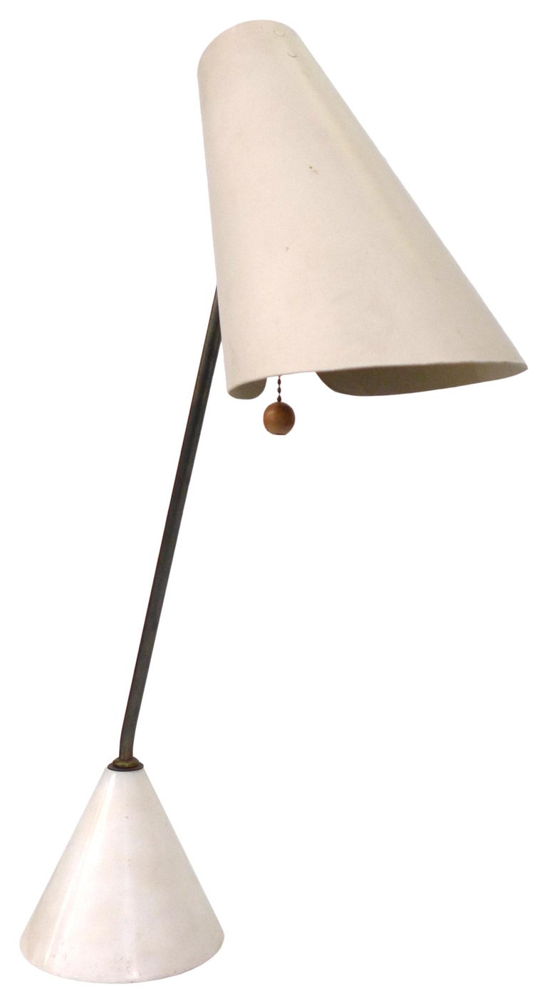An exceptional 1950s Italian articulating desk lamp by Raymor. An alluring, elegant design with conical marble base echoed by a tilted, enameled steel, conical shade set on an angled brass stem, cleft to accommodate a dangling, wooden sphere pull.