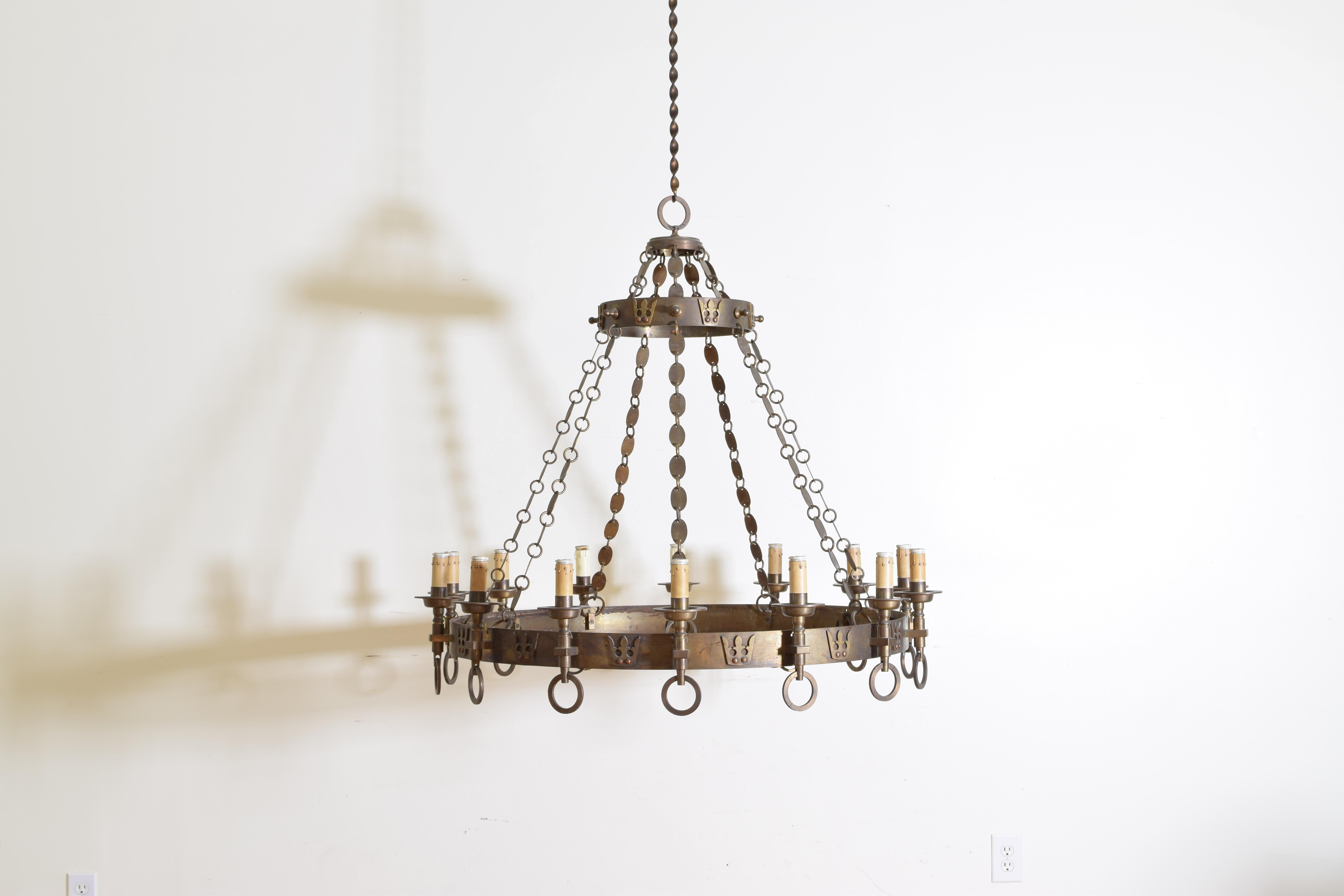 The chandelier having two concentric rings decorated with crowns, with 14 torcheres attached to the outers, the rings connected by oval brass disks.