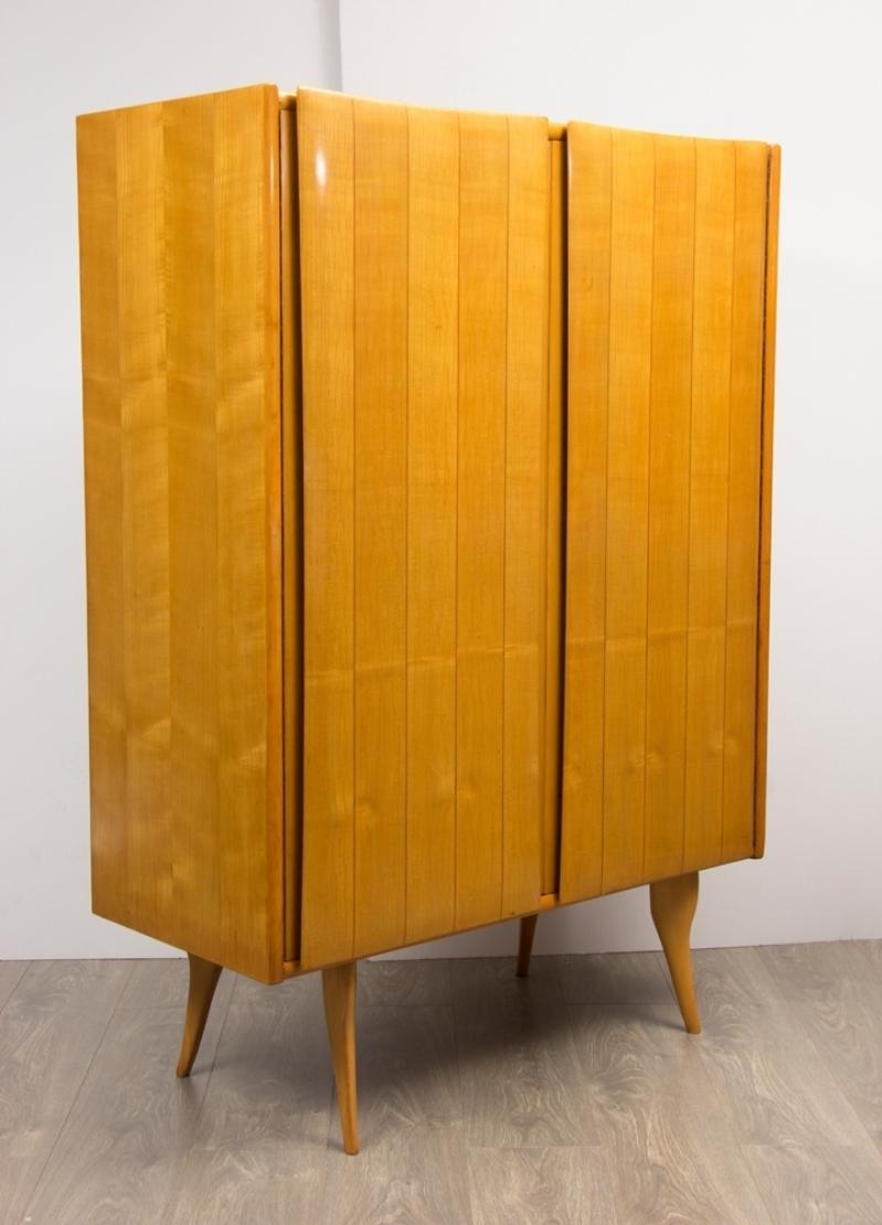 An Italian midcentury cabinet made in a striped golden Ash with internal glass shelves and raised on slender tapered legs.