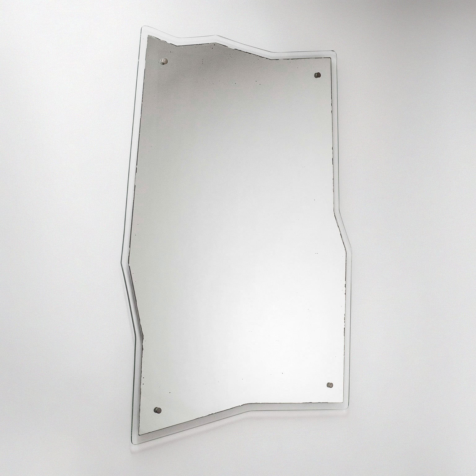 Rare Italian asymmetric mirror from the 1950s. Frameless, with a clear edge, this sports a floating mirror with a seemingly freestyle jagged shape. 
Measures: Height 104cm (41?), Width 76/64cm (30/25?), Depth 3cm (1.2?).