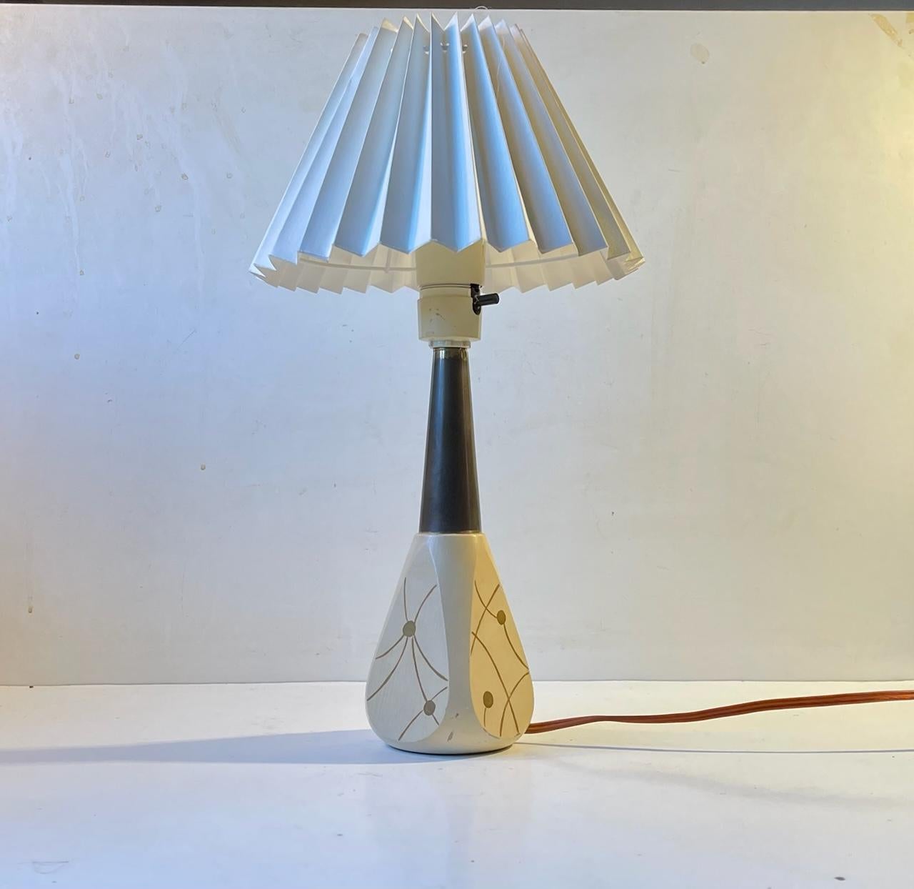 Lampe de table italienne des années 1950 composée d'un socle en bois laqué à décor atomique imprimé à la main, d'un plateau en laiton et d'un abat-jour en acrylique cannelé blanc. Il a été fabriqué en Italie dans les années 1950 dans un style qui