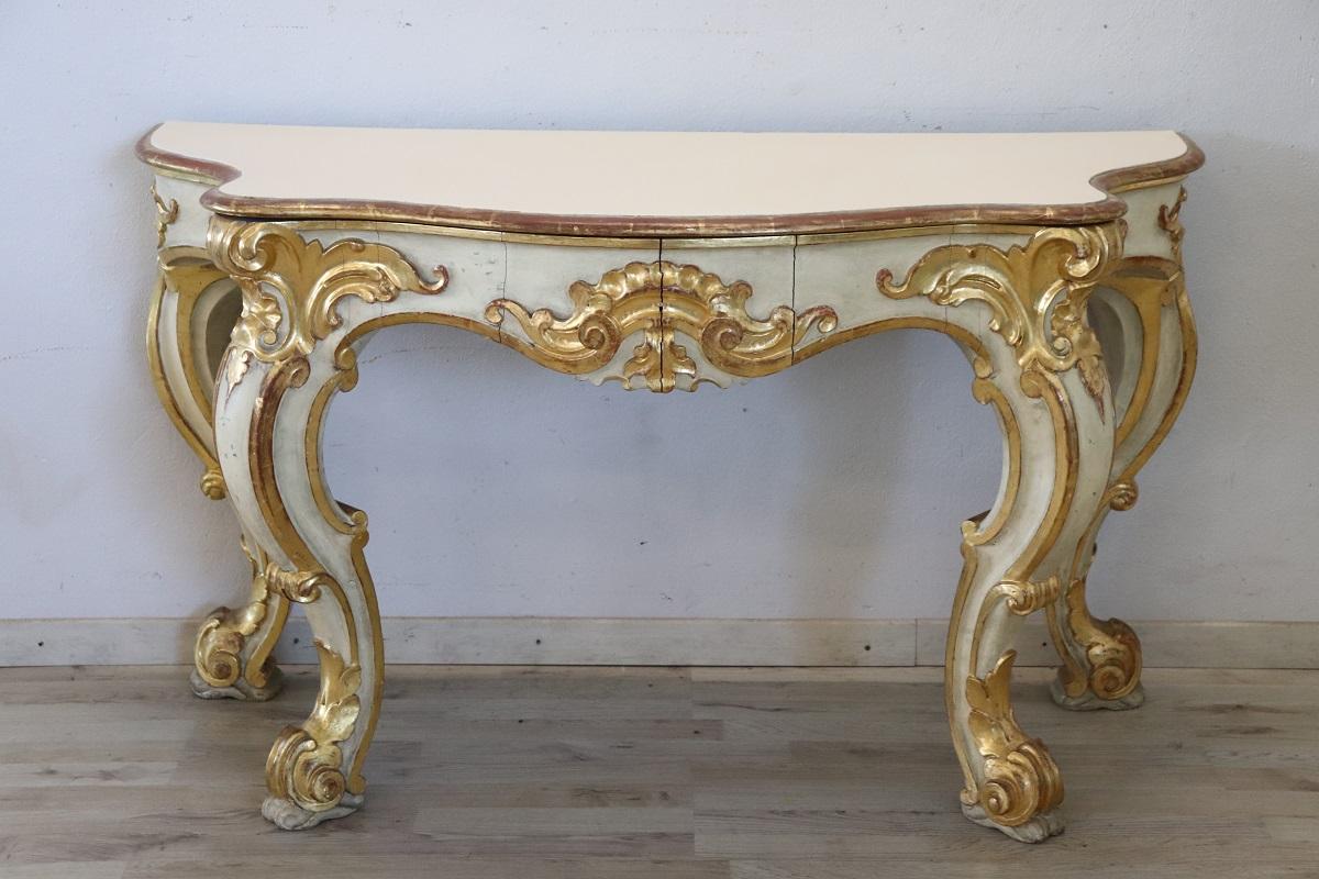 Beautiful majestic italian console table in Baroque style, 20th century. Made of wood with wavy legs and characterized by a refined decoration carved in relief with acanthus leaves, shells and curls. The base is lacquered, while the relief