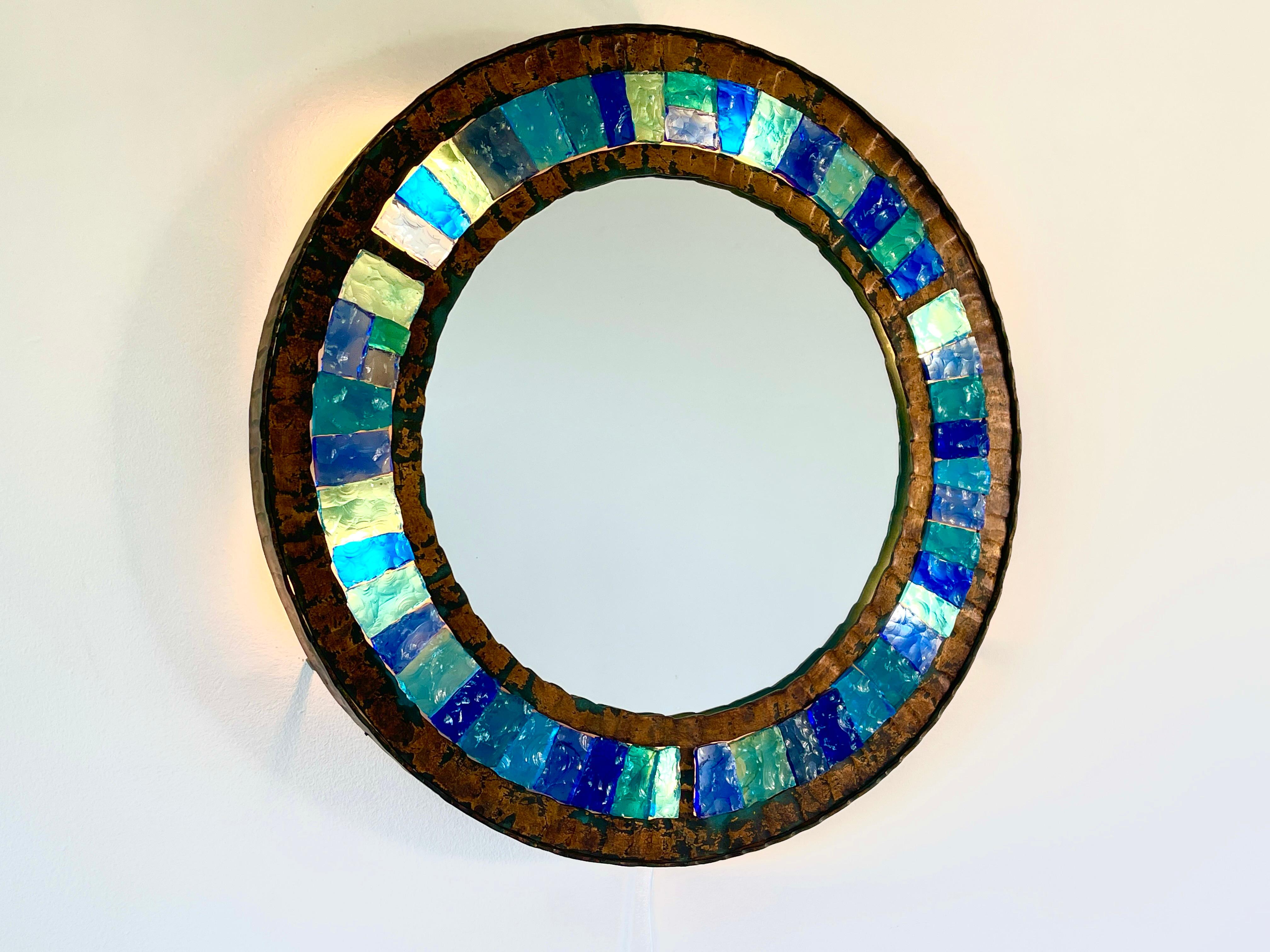 Rare backlit wall mirror manufactured by Longboard in Verona, Italy - 1970's.
Hammered glass and gilt gold leaf wrought iron in brutalist style.
Gorgeous original glass in various hues of turquoise. 
Newly rewired and lights up from behind. 
 