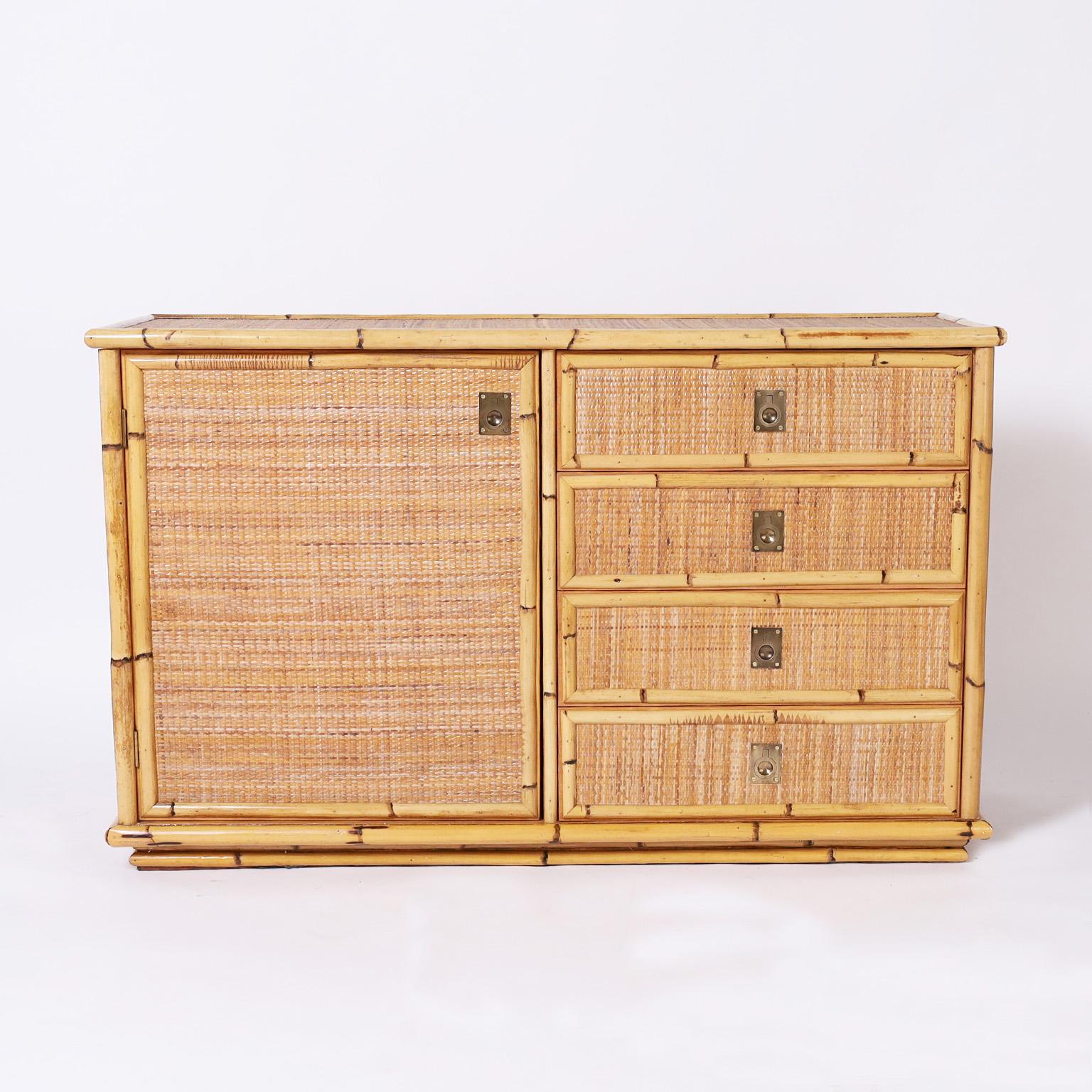 Mid century cabinet or chest with a bamboo frame, grasscloth panels all around, campaign style brass hardware, a cabinet door and four drawers. Signed Dalvera on the door. 