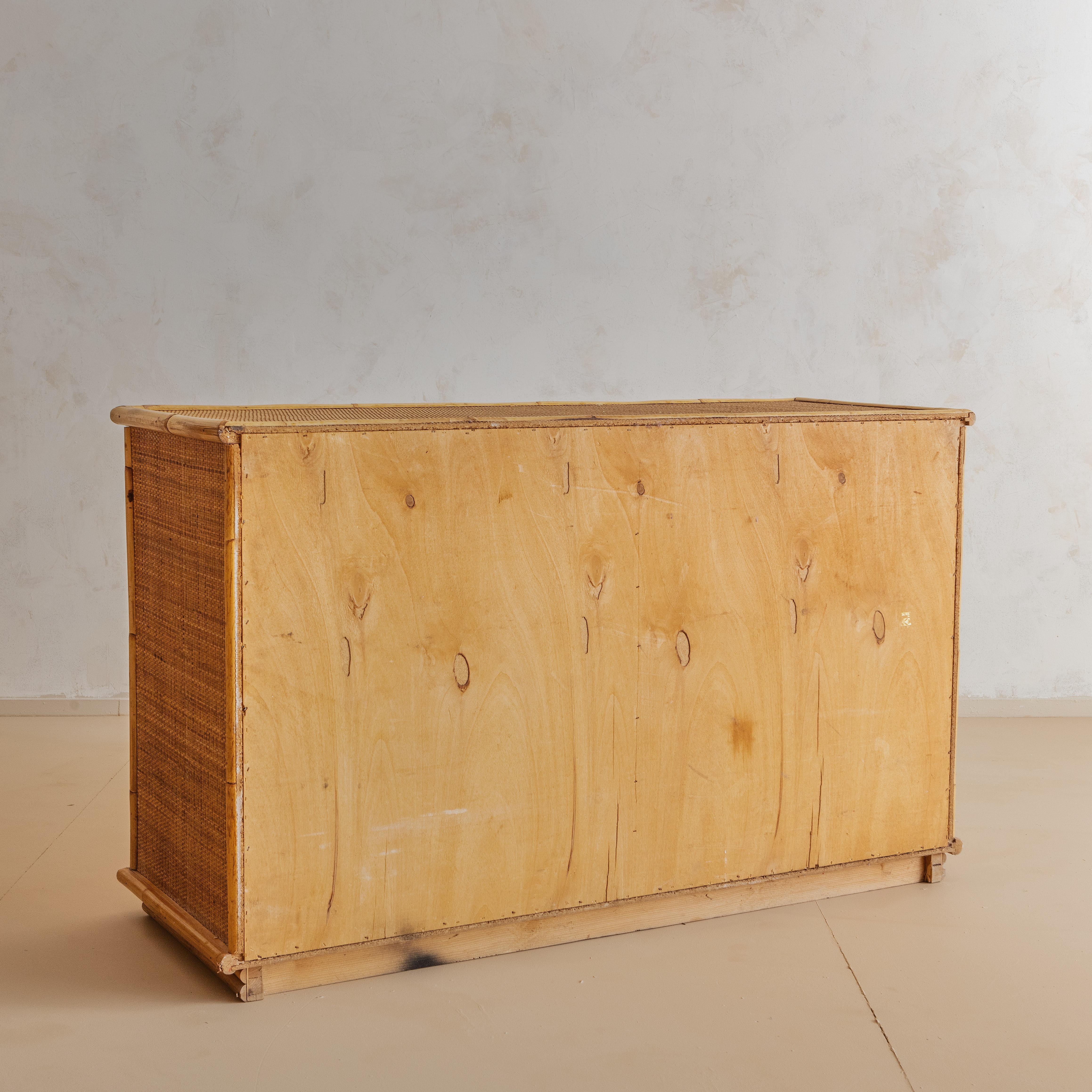 A 1970s Italian Bamboo and Rattan Dresser that highlights the warmth and durability of these these natural materials. On the right hand sider are four drawers that glide open with ease. On the left hand side a single cabinet door opens to reveal a