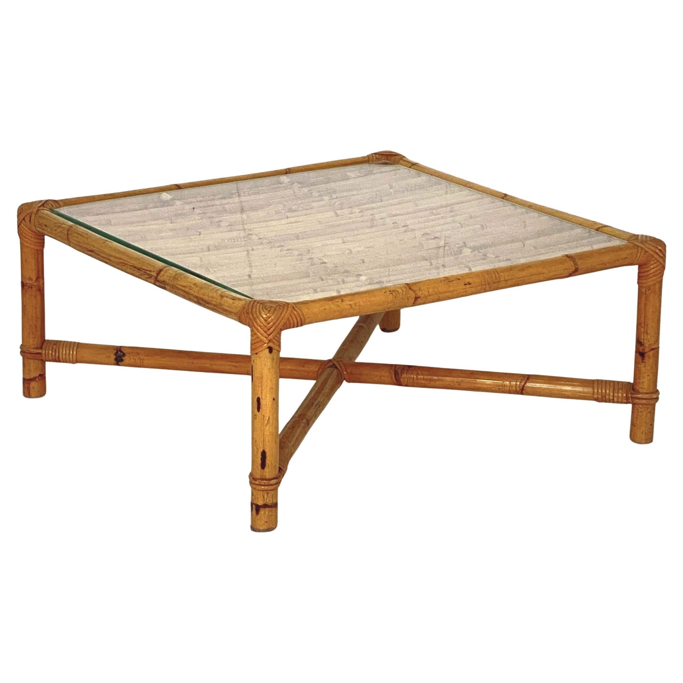 A fine Italian Mid-Century Modern bamboo and rattan low or coffee or cocktail table with removable glass top - featuring a square frame of woven wicker rattan and bamboo with a parallel grid top over four legs with a crossbar brace and an optional