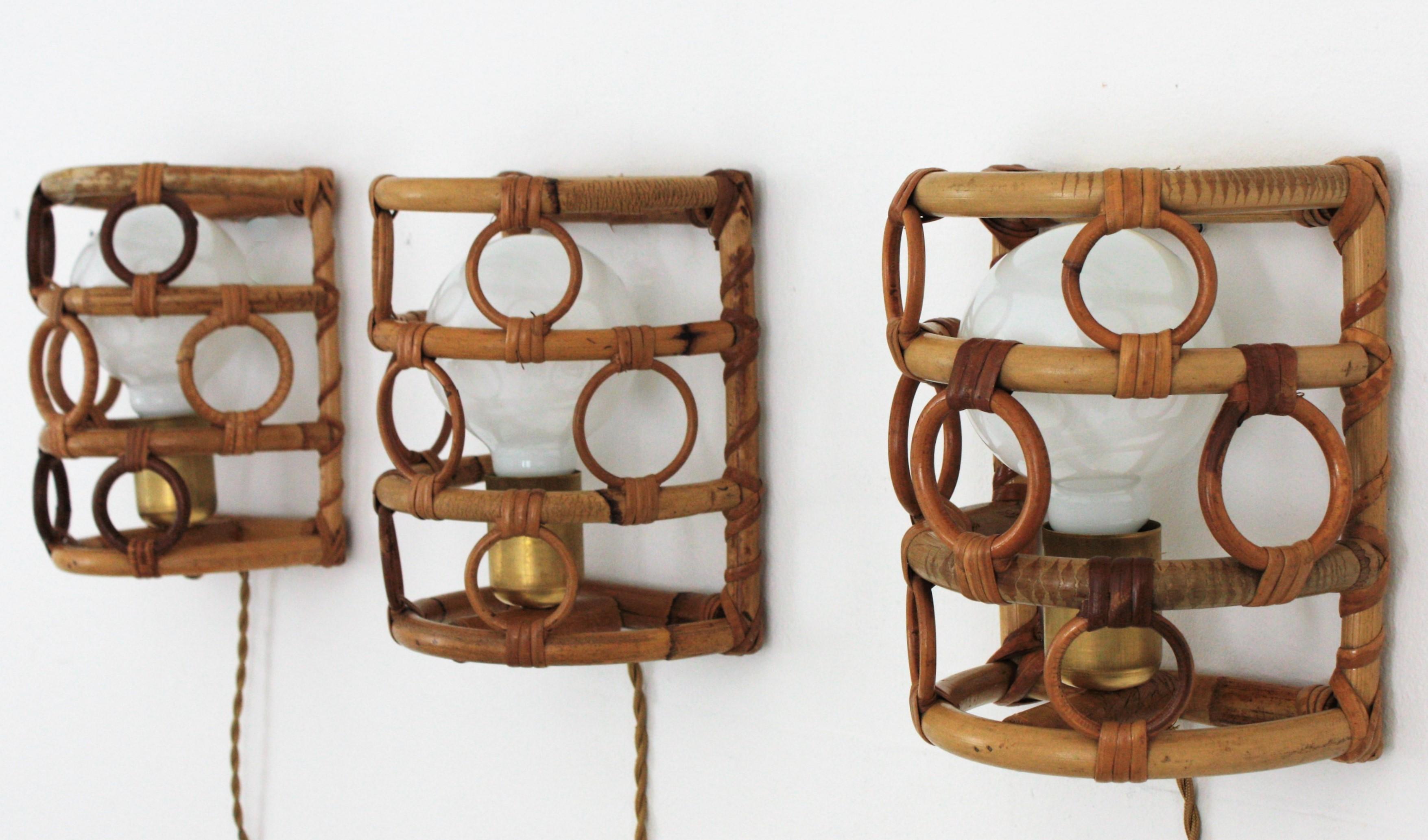 Set of three half cylinder wall lights with bamboo and rattan shades accented by circles, Italy, 1960s.
These light fixtures have a bamboo semi cylindrical structure adorned by rattan round rings. They have a brass cover to hide the bulb