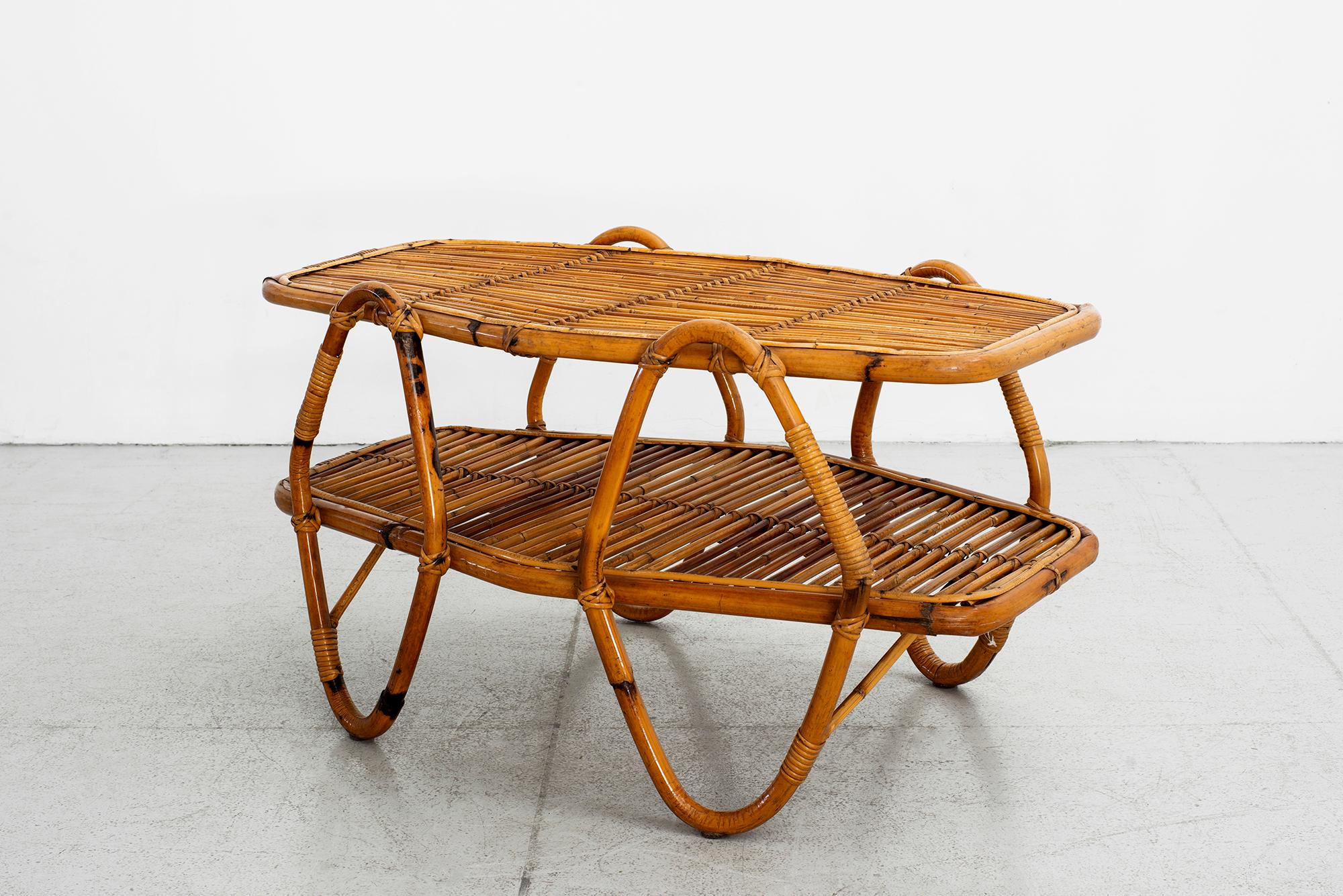 Uniquely shaped Italian bamboo coffee table with angular loop legs
Two tiers with shelf for books.

   