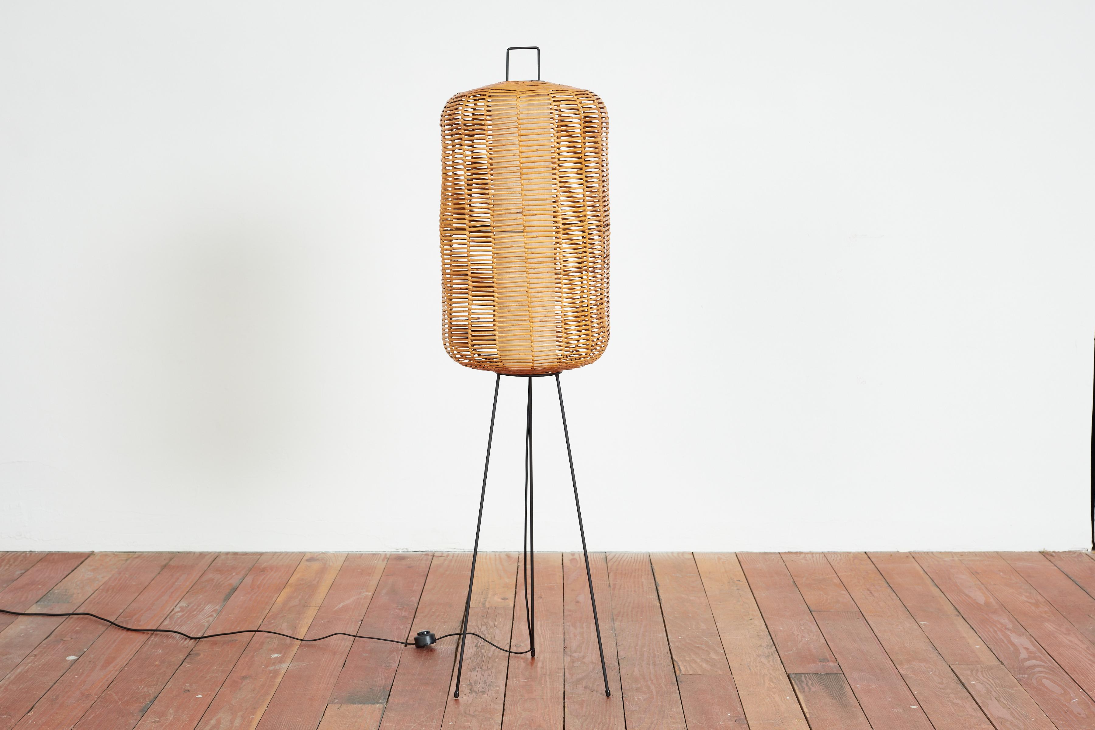 Simple Italian bamboo and iron floor lamp with tripod base and cylinderical center diffuser. 
Woven rattan creates a beautiful glow. 

Italy, 1950s