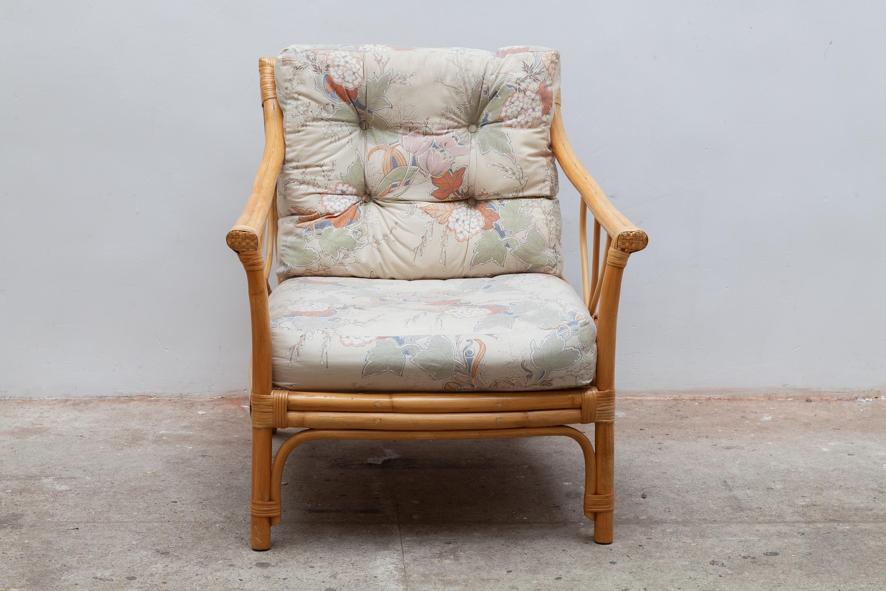 Confortable chaise longue en bambou vintage des années 1970. Cadre décoratif robuste avec accoudoirs. Coussins floraux en tapisserie d'origine, bon état.