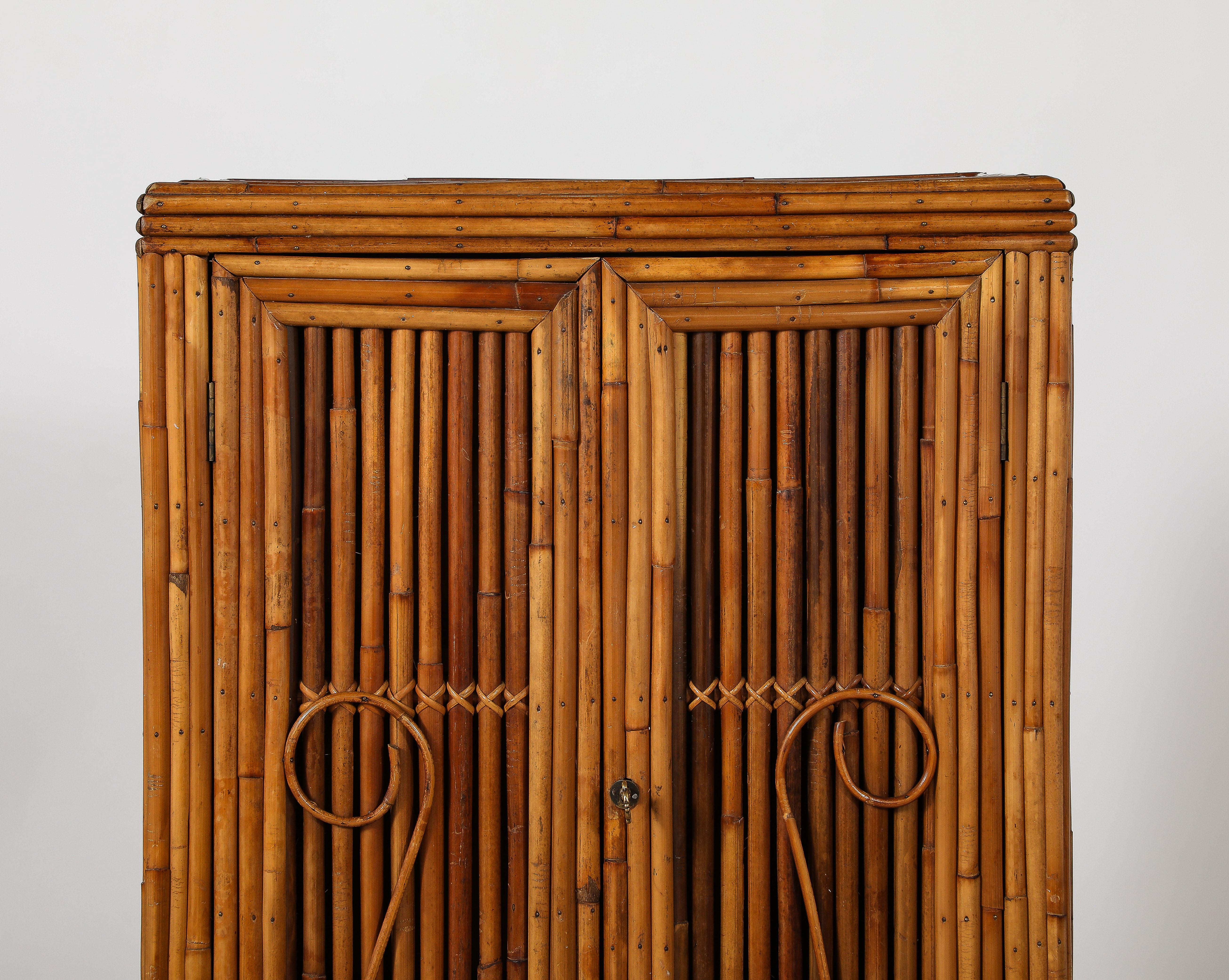A wonderful and charming Italian two-door bamboo cabinet with three interior shelves and decorative scroll motif on the doors.  A practical and whimsical piece for the kitchen or the great room.  With fanciful original key. 
Italy, circa 1950 
Size: