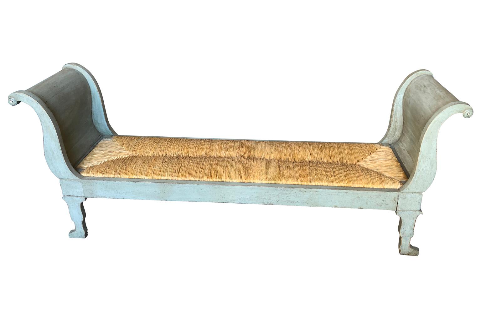 A delightful Italian later 19th century banquette in painted wood and rush seat. Wonderful form. Perfect at the foot of a bed or under a picture window. The seat height is 14 3/4