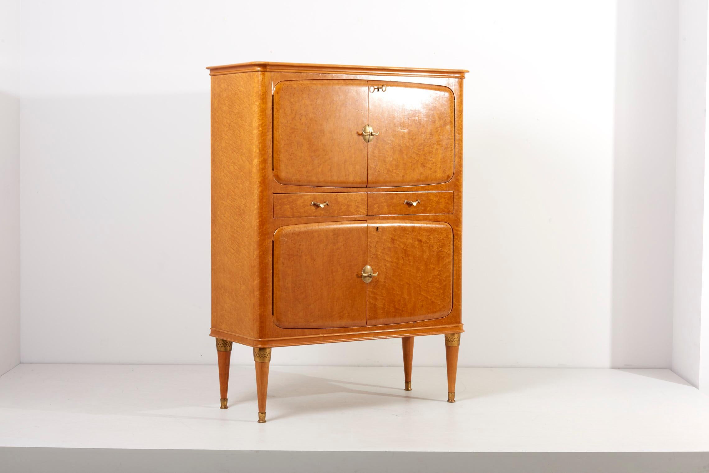 Italian Cabinet in Birdseye Maple, 1950s and mirrored interior and inside lighting.
The shapes and form language so as the hardware is very unique and well made. I would consider this cabinet being in a fantastic condition. The brass details on the