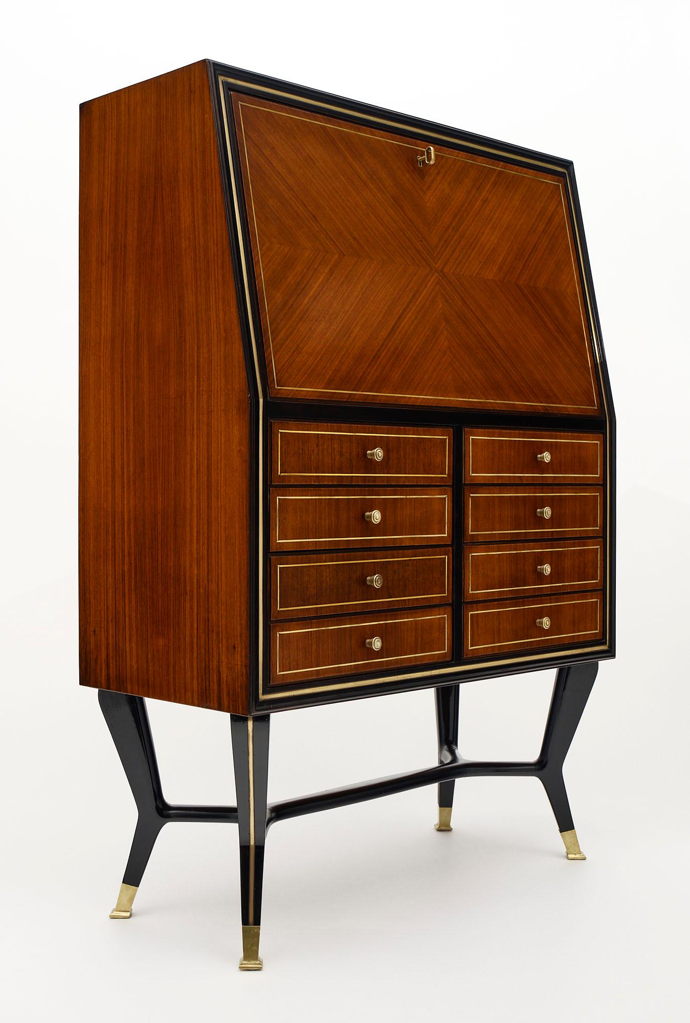 Bar / secretaire from Italy made of Brazilian rosewood. There are eight dovetailed drawers below with gilt trim throughout. The drop font opens to a glass lit interiors (rewired to US standards. This piece is in the manner of designer Paolo Buffa.