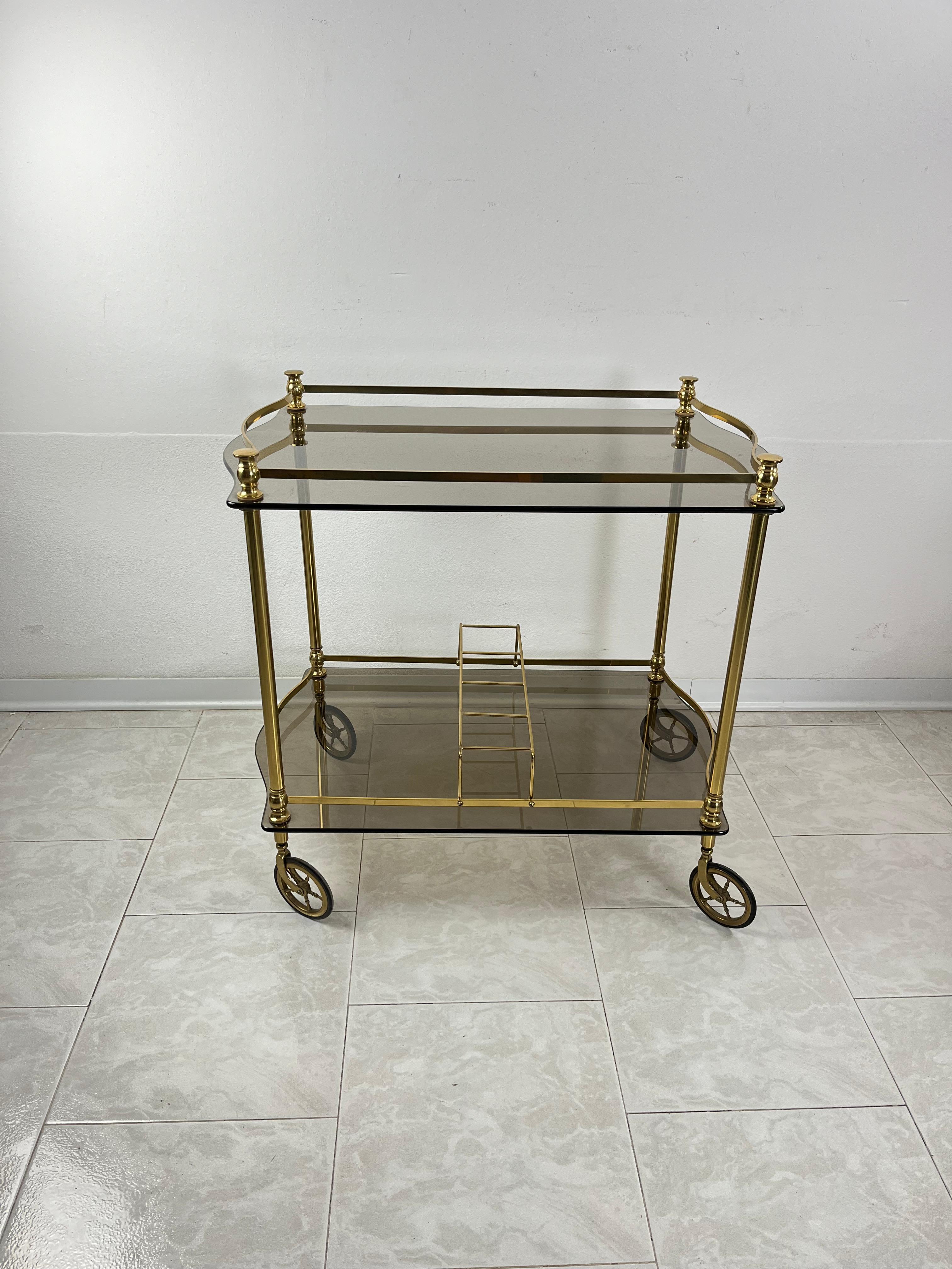 Chariot de bar italien en laiton et plateaux en verre fumé dans le style Hollywood Regency, années 1960
Intact et en bon état.
Elegant, il est doté de 4 roues pivotantes.