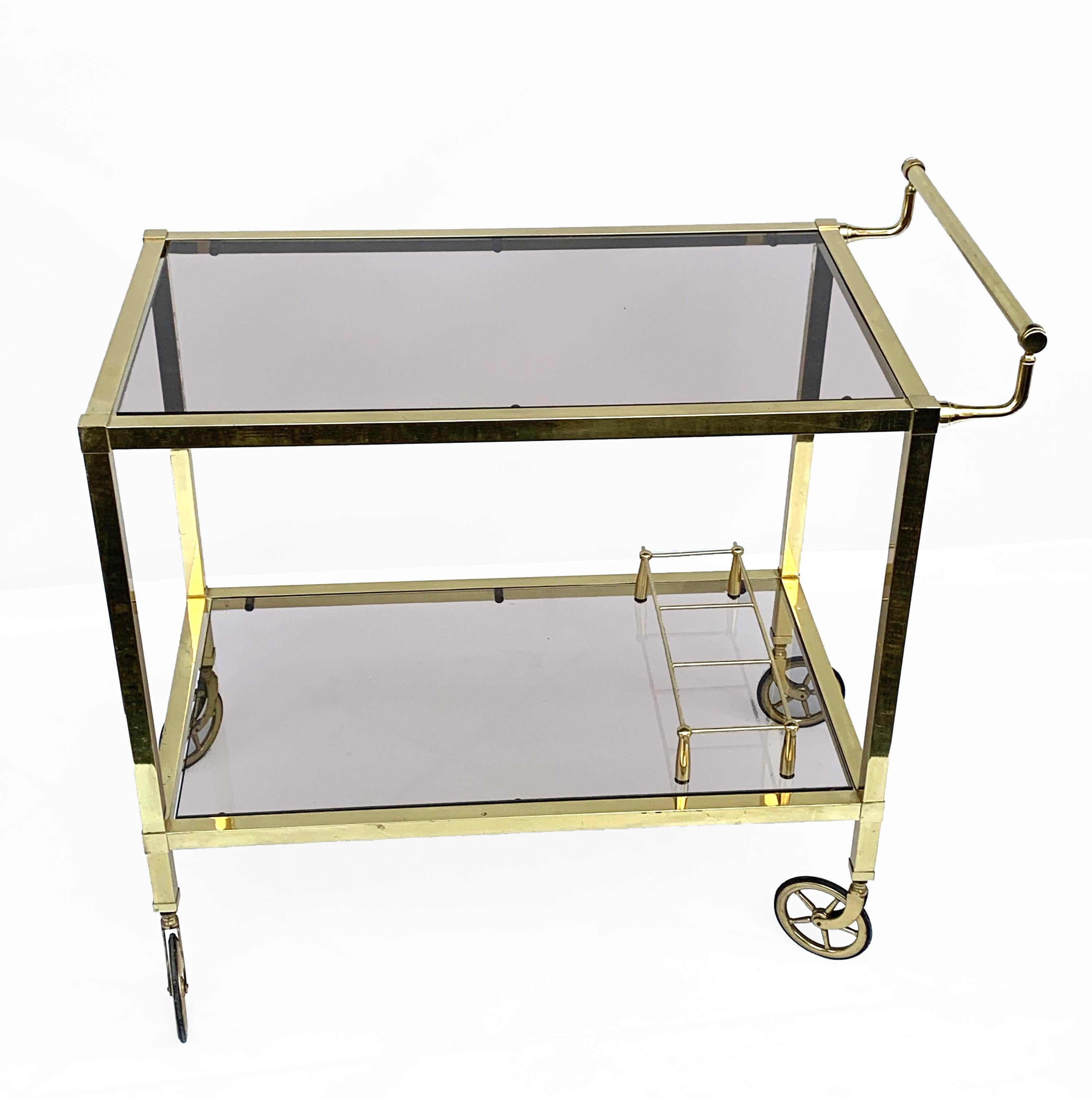 Exceptional two-level service cart from the Italian manufacturer.
Bar cart on two levels and smoked glass, Italy 1970s gold-plated.
Brass with bottle holder.