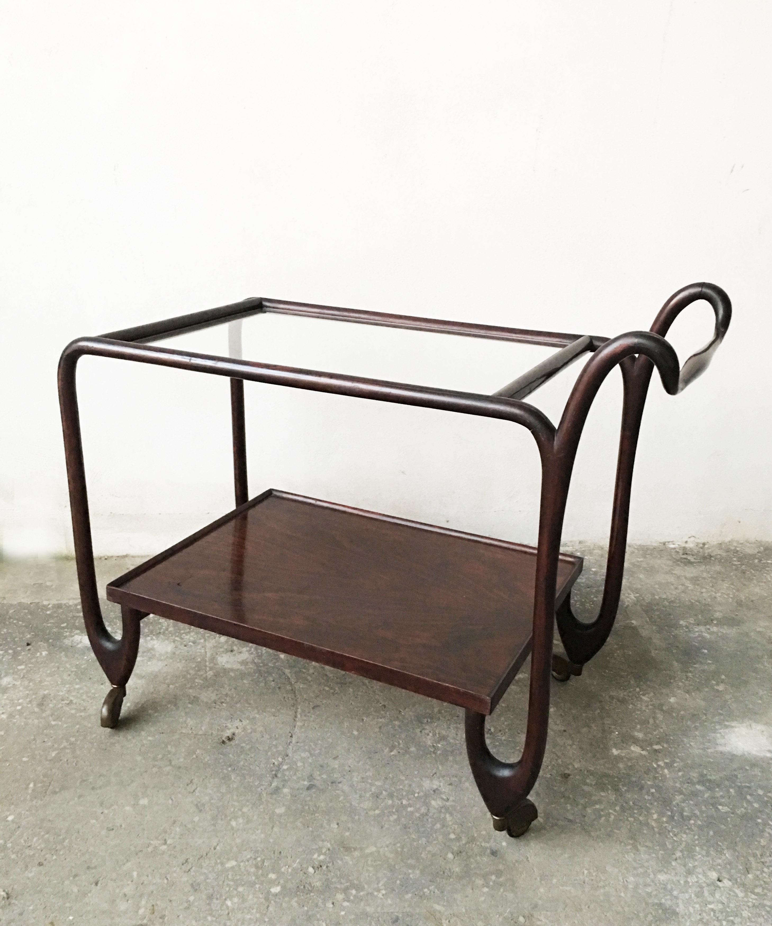 Amazing bar cart or trolley with curved mahogany with clear glass on top and four brass wheels.
All the shape remember some beautiful pieces designed by Giuseppe Scapinelli during his Brasilian period. The lower surface is in mahogany too.