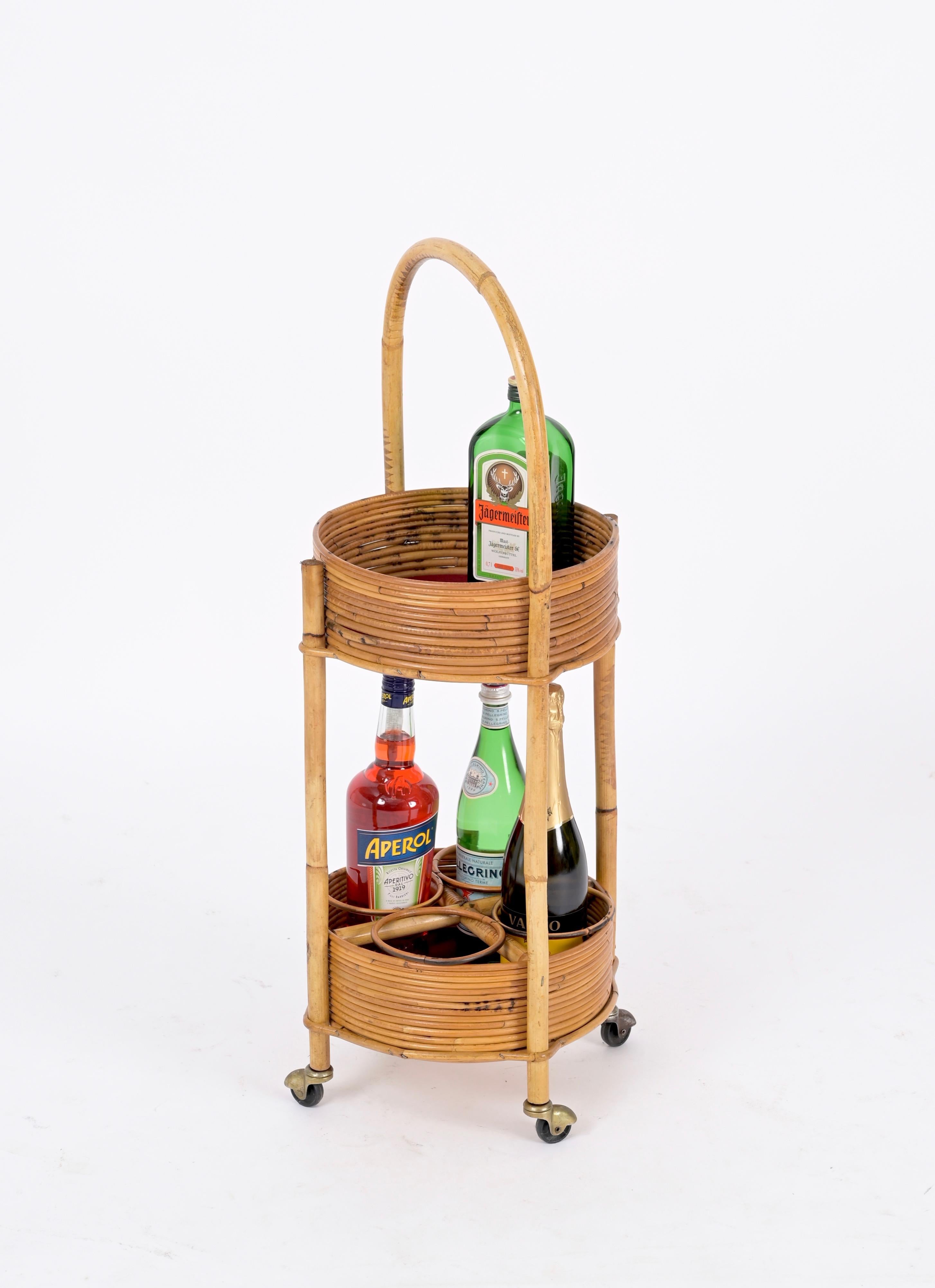 Lovely French Riviera style serving cart made in curved rattan, bamboo and velvet with brass wheels. This delightful object was made in Italy during the 1960s.

This gorgeous two tier bar cart has a round structure made in curved rattan and bamboo,