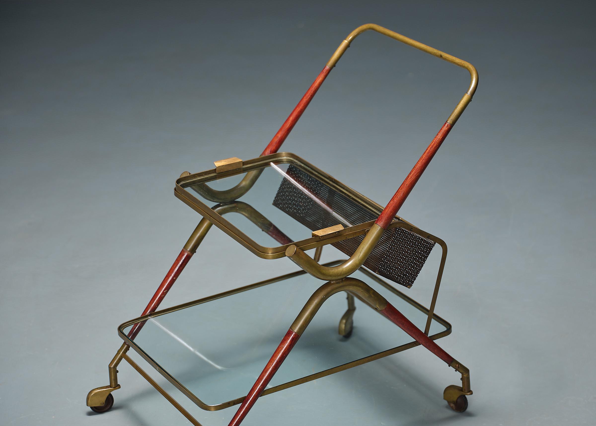 Design/One du milieu du siècle, ce chariot de bar  des années 1950 présente une fusion de matériaux et d'art fonctionnel. Fabriqué en laiton, métal, bois et verre, le chariot présente une palette de couleurs frappantes avec un cadre rouge et laiton.