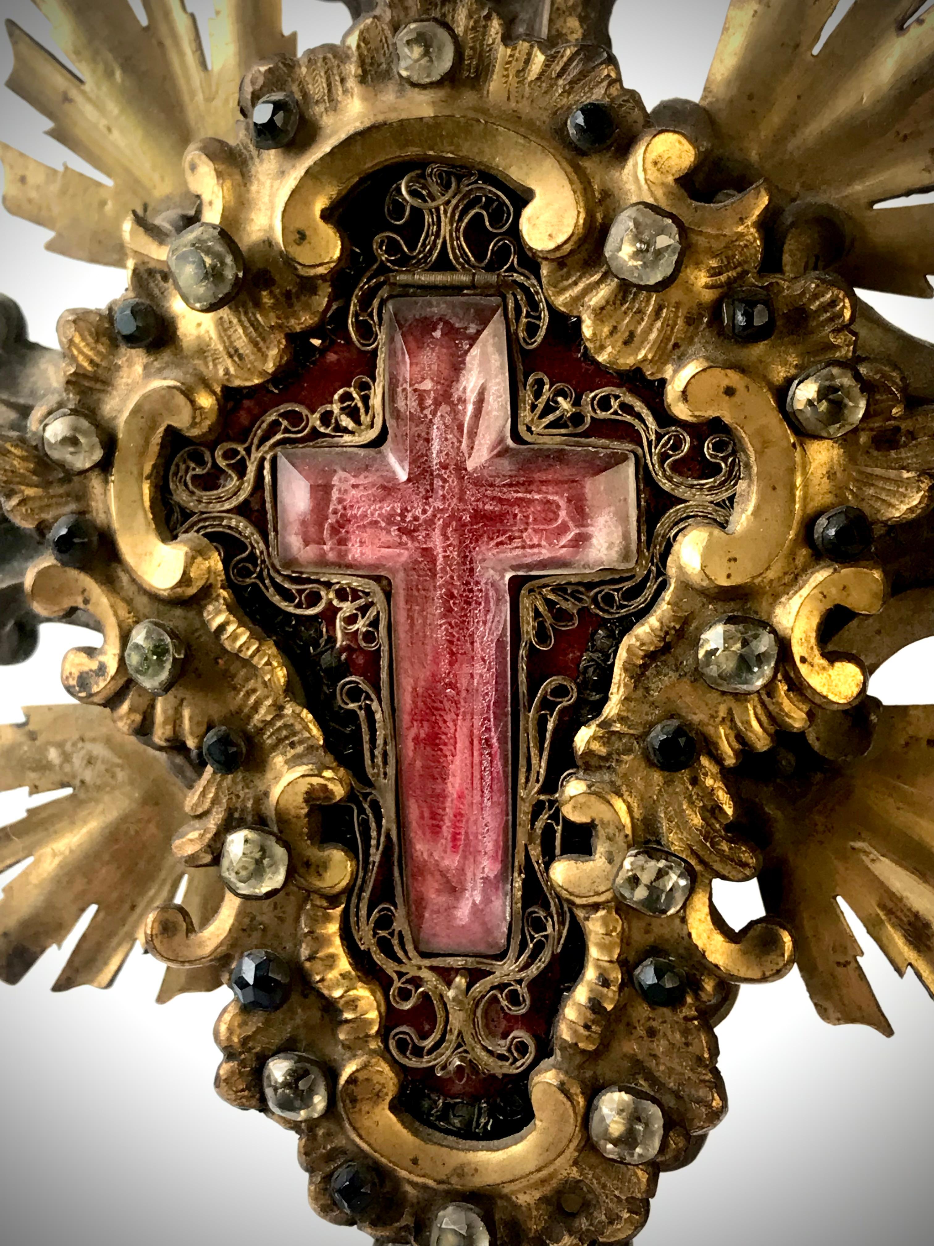 A magnificent 18th Century Baroque Gilded bronze Cross, with a rock crystal true cross relic.

Italian, circa 1780
Embellished with semi precious stones and further silver and gold gilding.Also gold thread scroll around the rock crystal cross.

A
