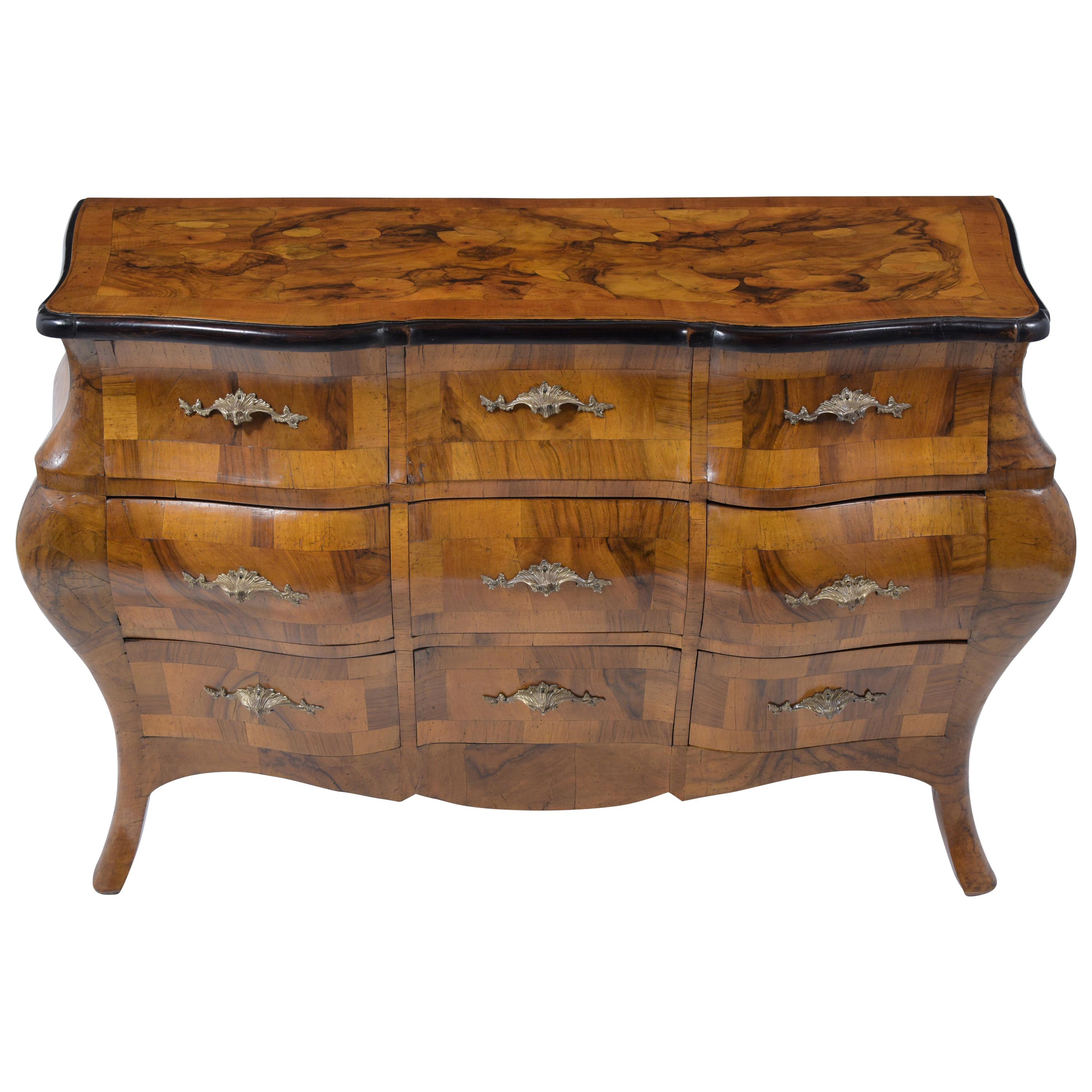 A remarkable early 1900s Italian chest of drawers crafted from solid maple wood covered with burl walnut veneers, a newly waxed patina finish, and has been fully restored by our team of craftsmen. This eye-catching dresser has been professionally
