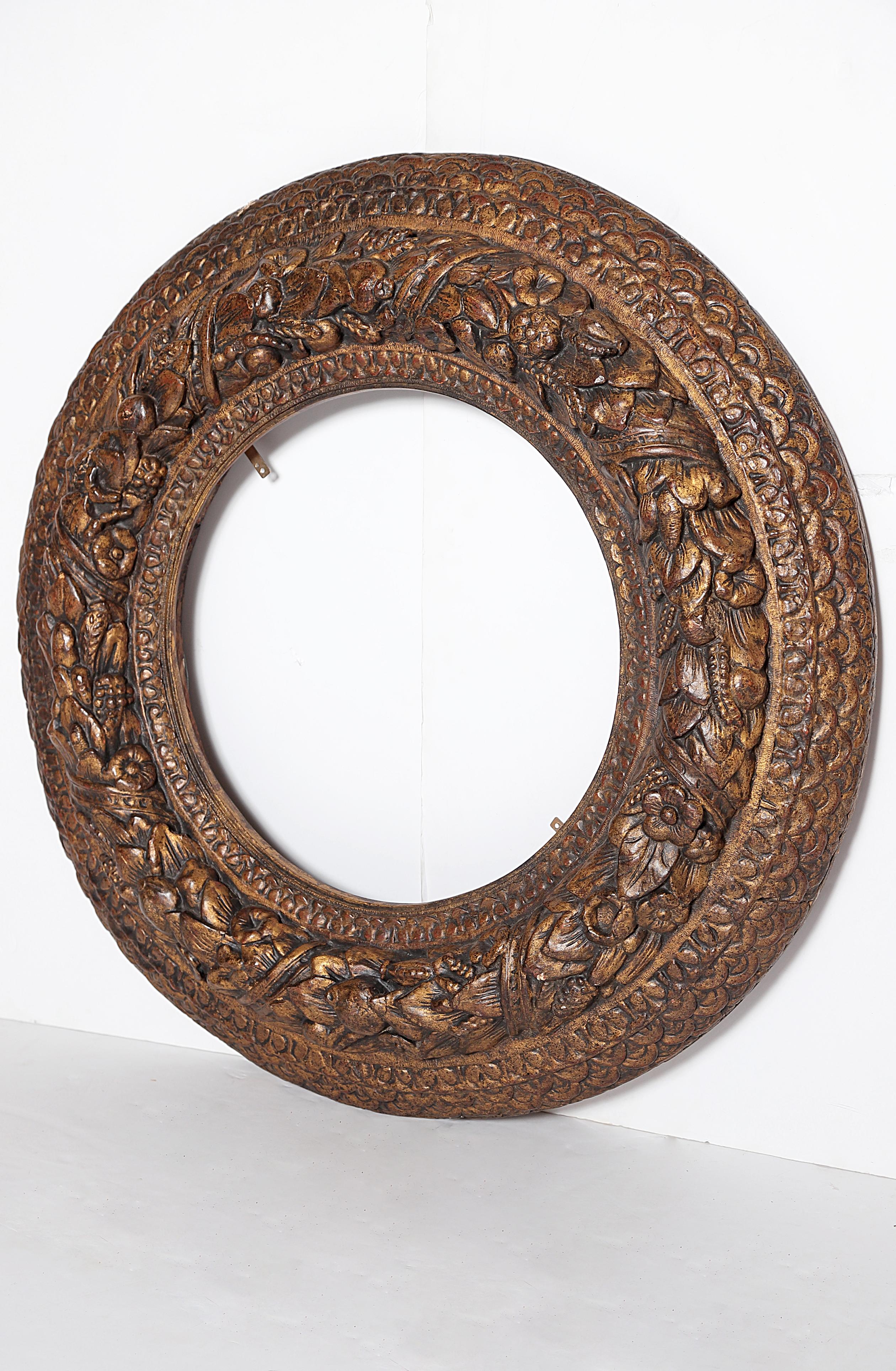 A heavily carved round picture / mirror frame, carved and gilded, rows of geometric and floral carvings, central circle has wheat sheaves embellished with flowers, Italian, late 17th century

Measures: 4.25