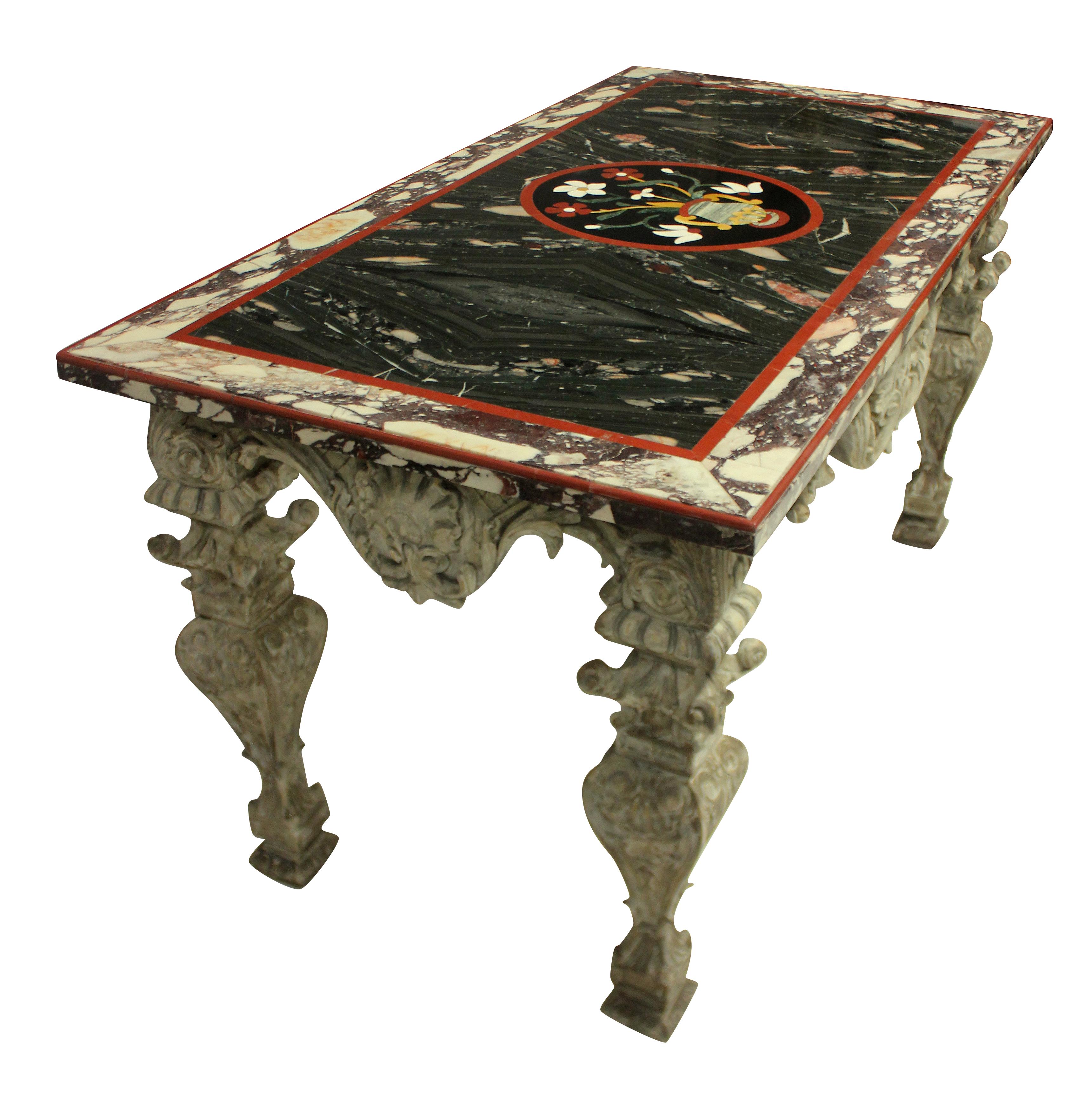 An Italian Baroque heavily carved and distressed painted walnut center table. With shell and acanthus detailing throughout, supporting a Pietra Dura marble top. The top in various marbles and hardstones, with a shaped carnelian edge, with a central