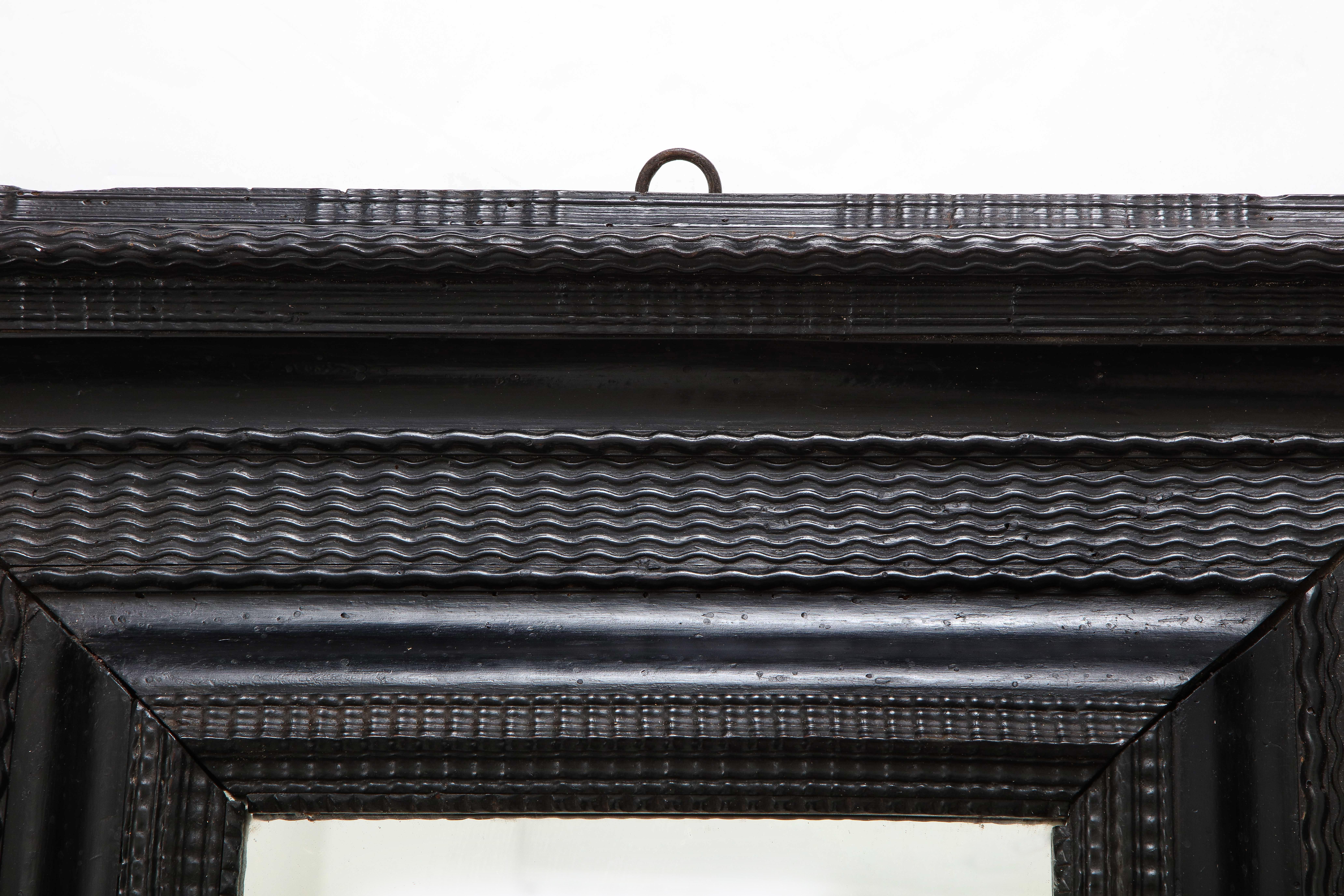 Eine außergewöhnliche norditalienische Barock kunstvoll geschnitzt ebonisiert Rahmen, mit alten Quecksilberglas eingesetzt. Der Rahmen ist mit einer geschnitzten Wellenleiste versehen und hat auf der Rückseite einen originalen geschmiedeten