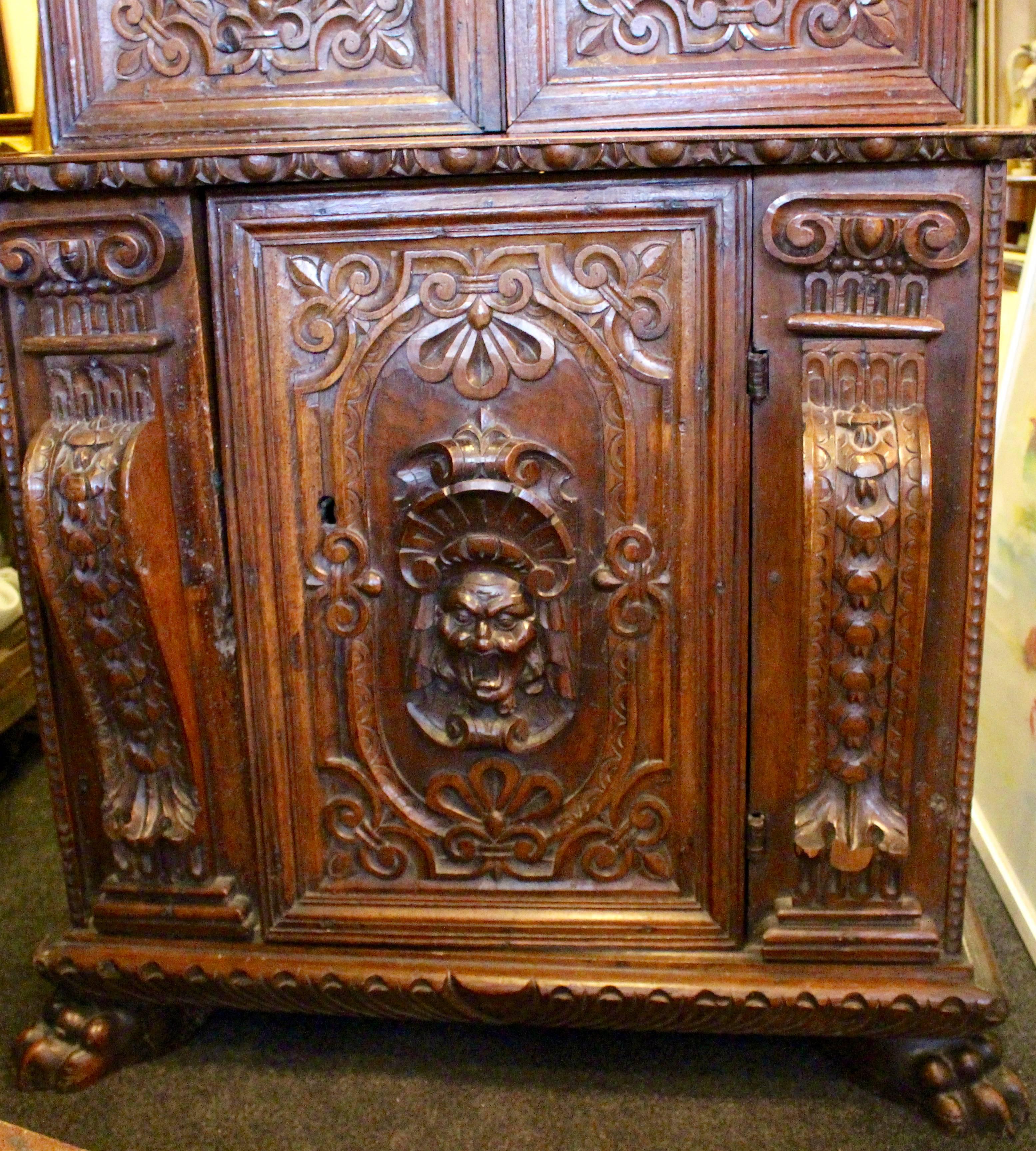 A stunning example of an early 17th century Italian cabinet. Heavily carved with egg and dart style pediment above upper cabinet with two beautifully carved doors, adorned with one happy and one sad face. Enclosing two shelves.
The lower cabinet