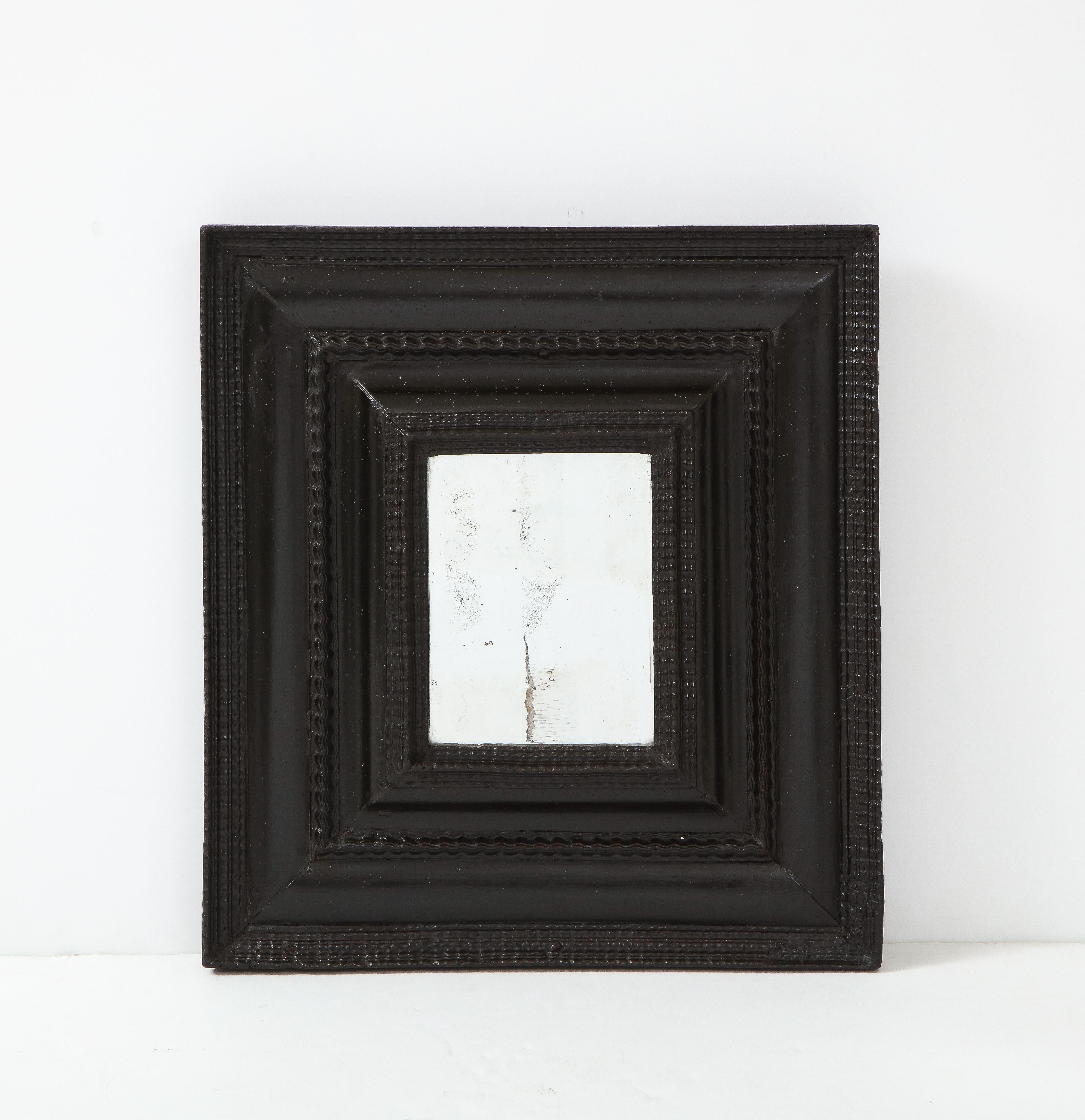Northern Italian Baroque ebonized walnut guilloché frame, inset with old mercury glass. A bold and dramatic sculptural statement piece for any interior style. 
Northern Italy, circa 1680-1700 
Size: 22 1/2