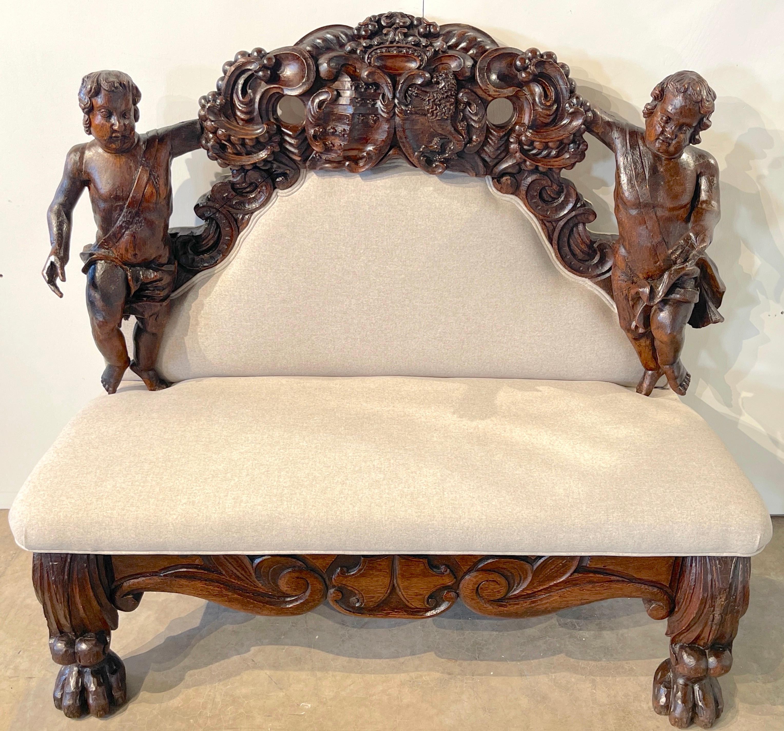 Italian Baroque Figural Bench/ Settee 
18th century or older, some later support added

A quietly stunning figural Italian Baroque Bench/ Settee, The upholstered backrest, flanked by two hand carved expressive putto (26-Inches high x 9-inches