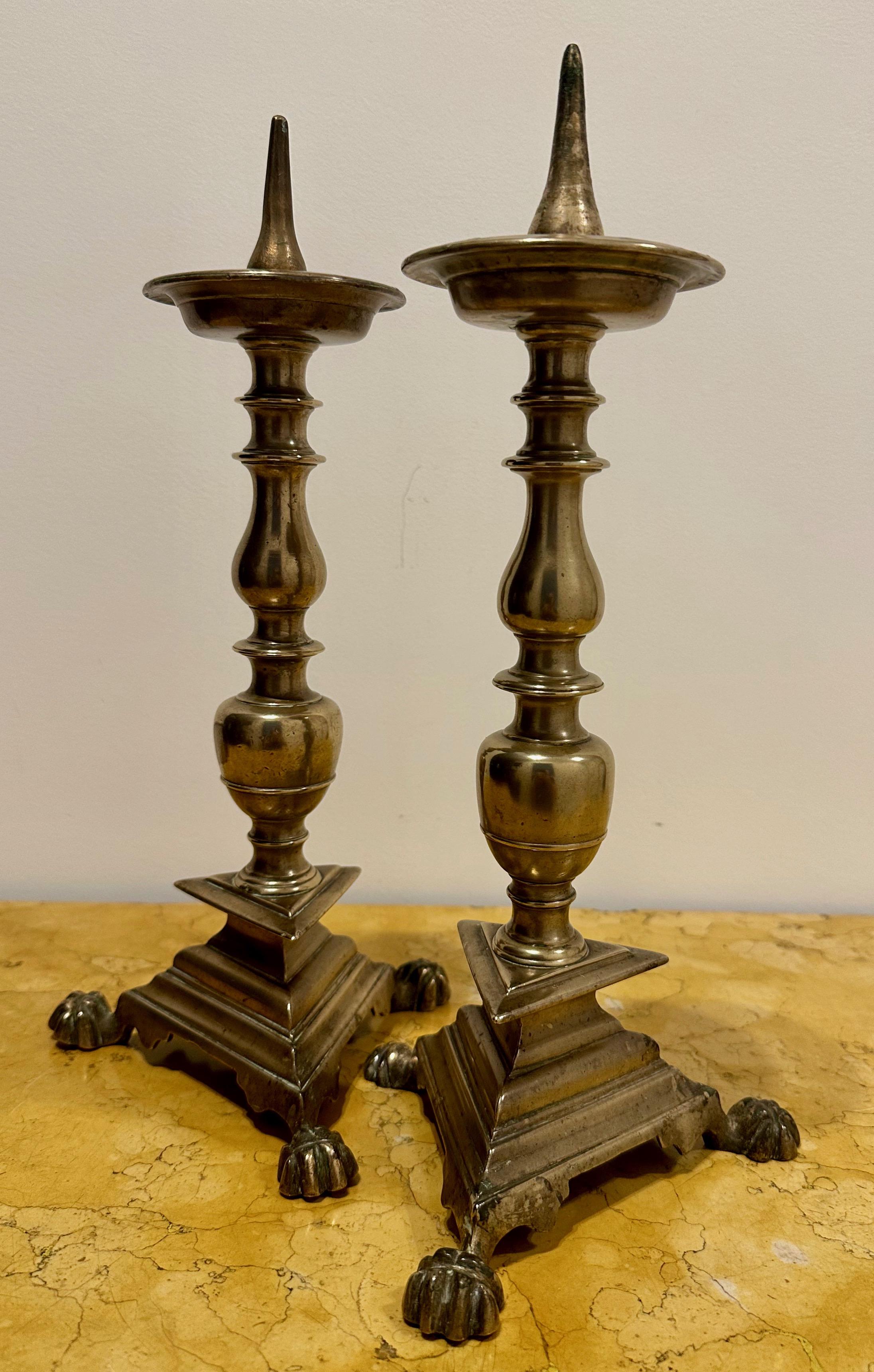Italian Baroque, Pair of Bronze Pricked Candlesticks, Late 17th Century

This Elegant pair of bronze candlesticks of the late 17th century, are resting on a tripod base sitting on claw feet. The central turned baluster is topped by a large cup that