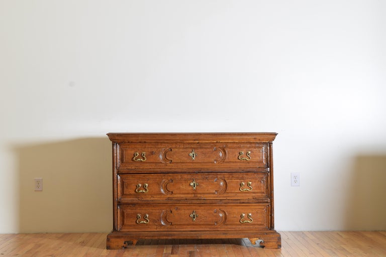 From the region of Tuscany this Baroque chest is constructed of a light walnut with a subtle, likely, pearwood inlay, with pronouned carved panels on the drawer fronts, paneled sides, and raised stiles at the front sides connect the case to the