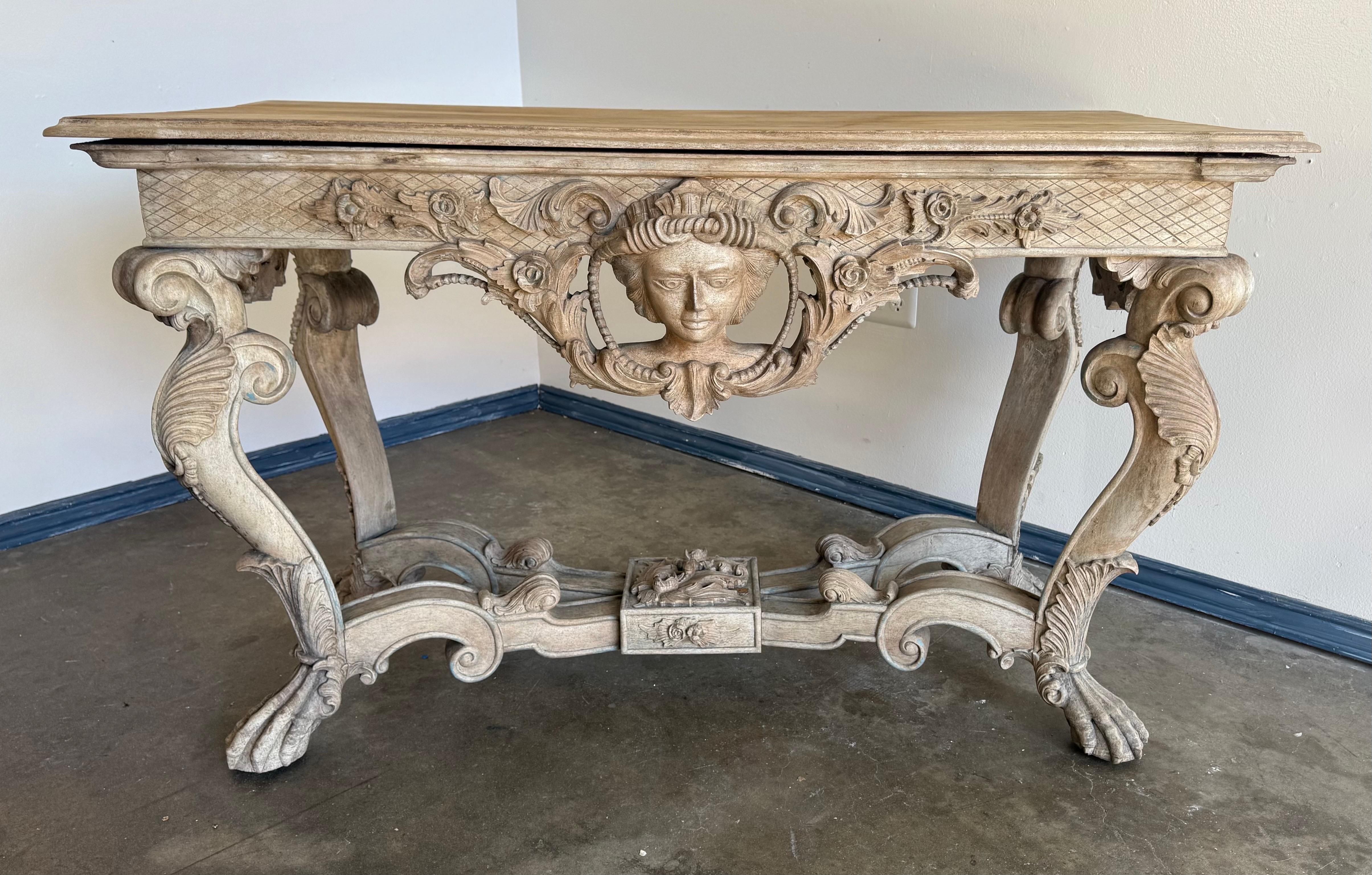 A highly decorative Italian carved wood console table, late 19th century, executed in the Baroque Revival style. The frieze is centered with a dramatic female mask in deep relief, surrounded by scrolling acanthus, floral garlands, and latticework
